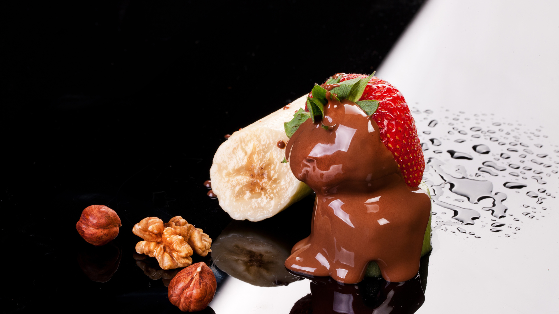 Клубника в шоколаде, банан и орехи на черной поверхности