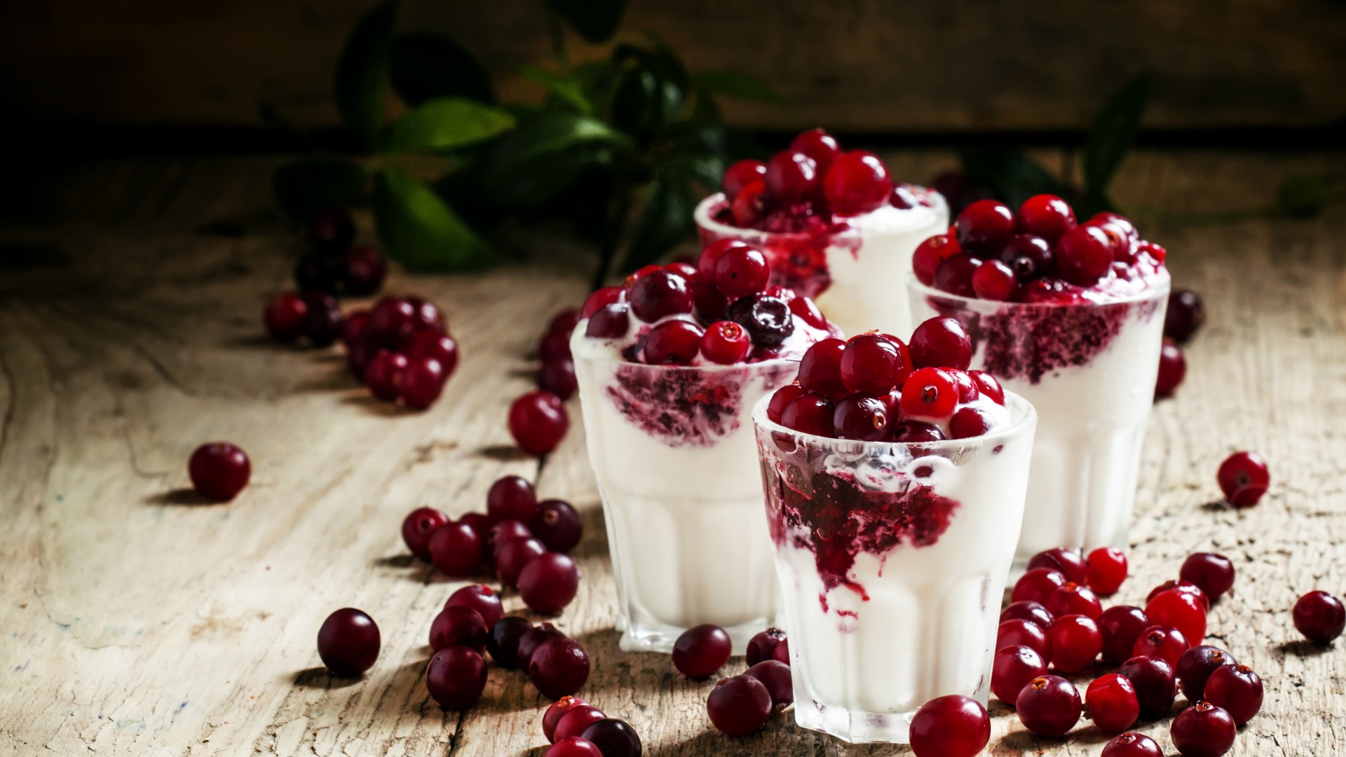 Сладкий десерт с клюквой в стеклянных стаканах