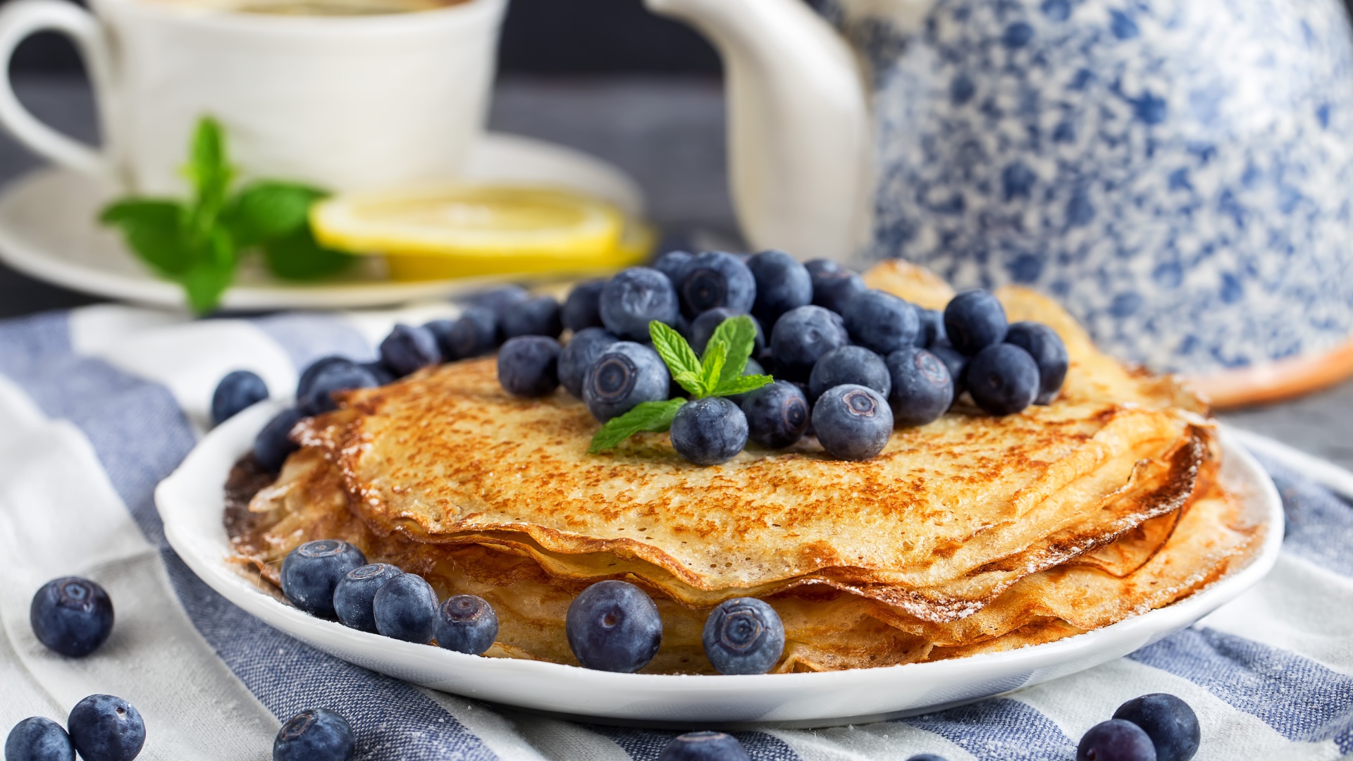 Тонкие блины с ягодами черники на столе с чаем