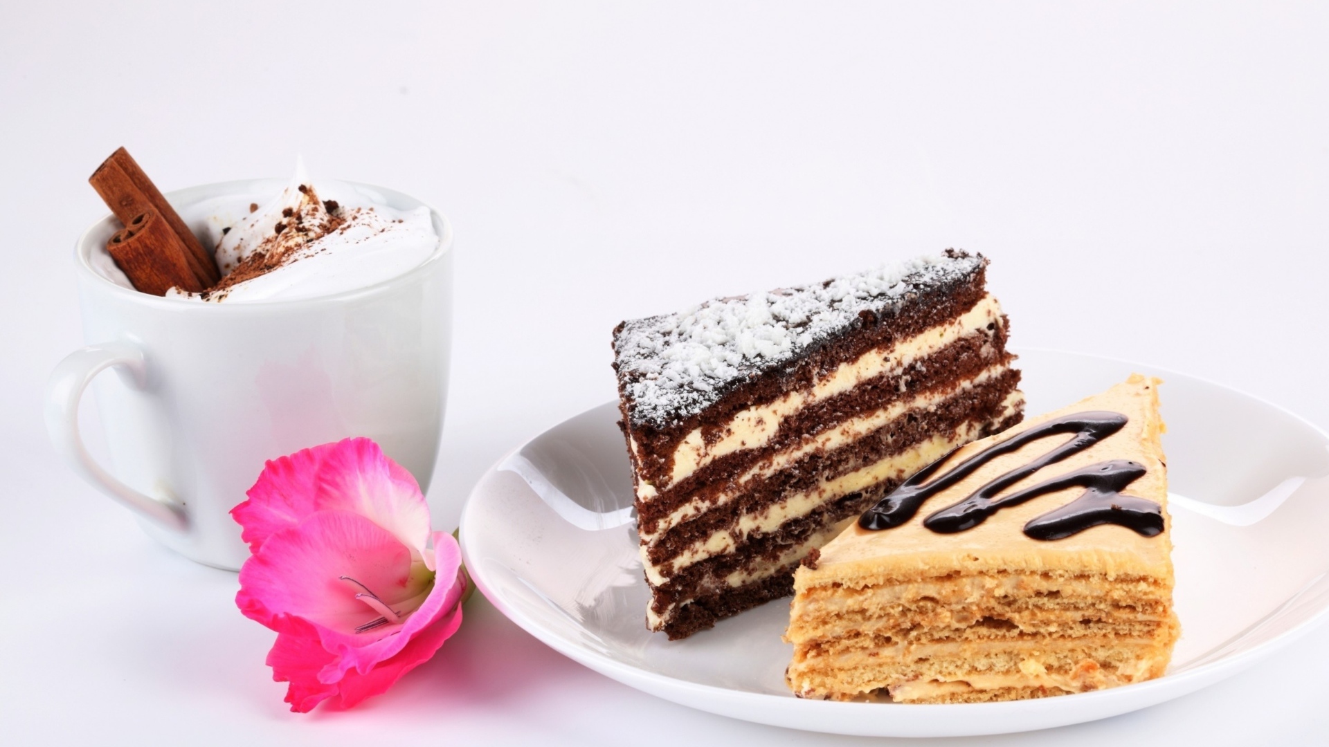 Два куска торта на столе с чашкой кофе и розовым цветком