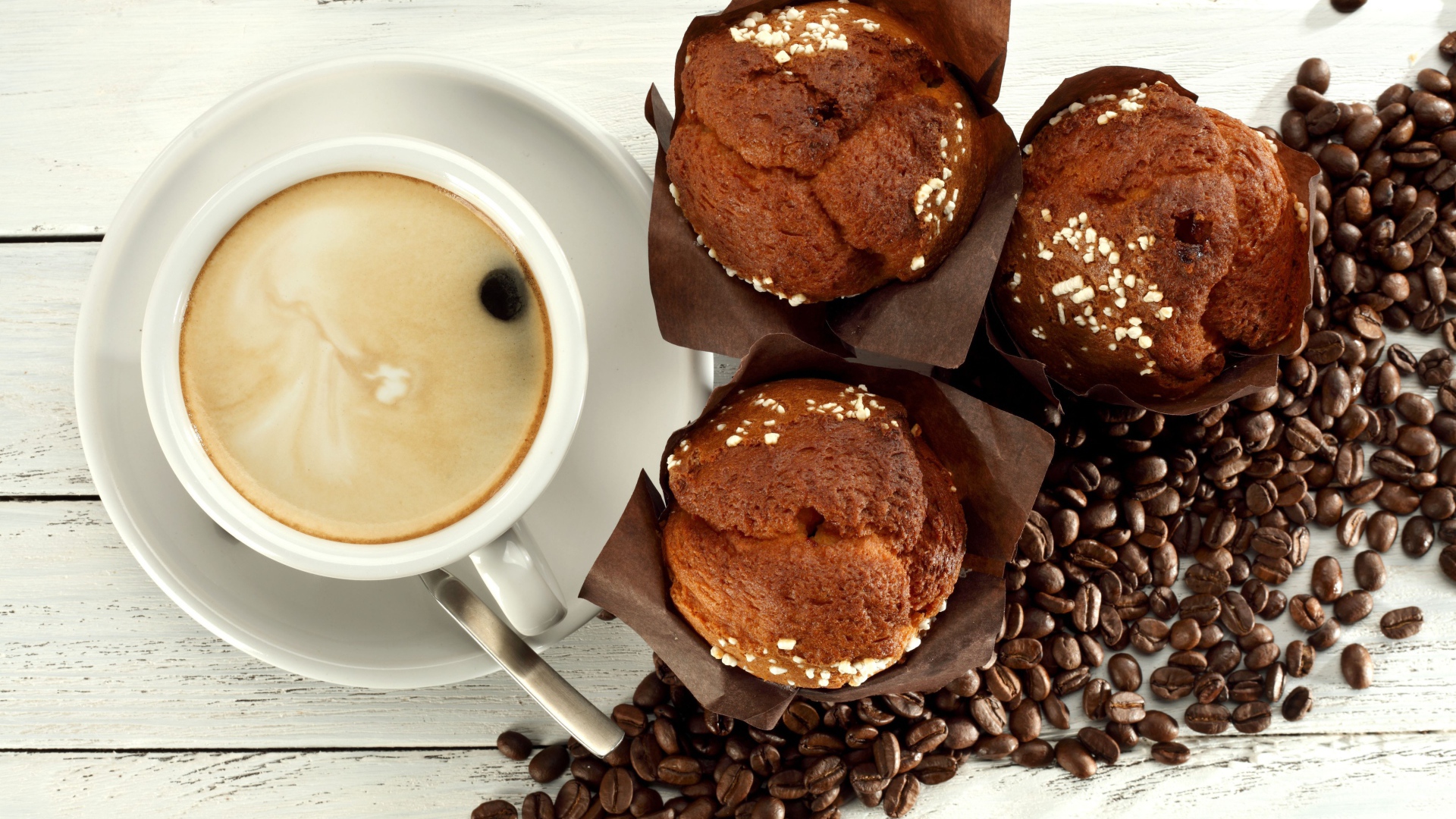 Чашка кофе с кексами и кофейными зернами на столе