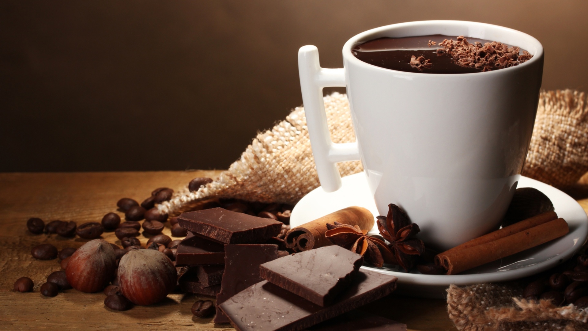 Чашка горячего шоколада на столе с корицей, бадьяном и фундуком