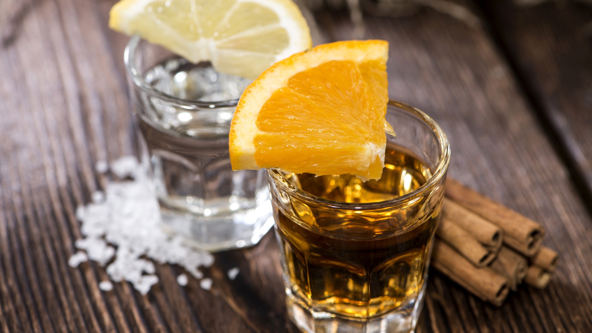 Рюмка водки и рюмка виски на столе с кусочками лимона