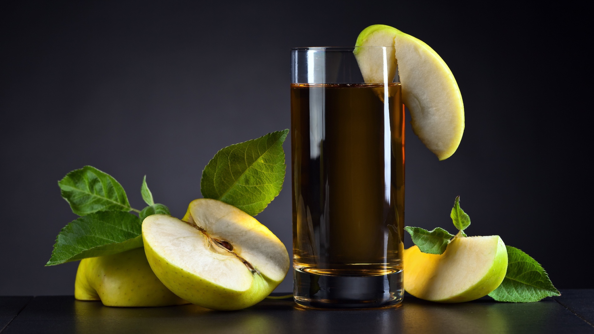 Яблочный сок в стакане на столе со свежими яблоками на сером фоне