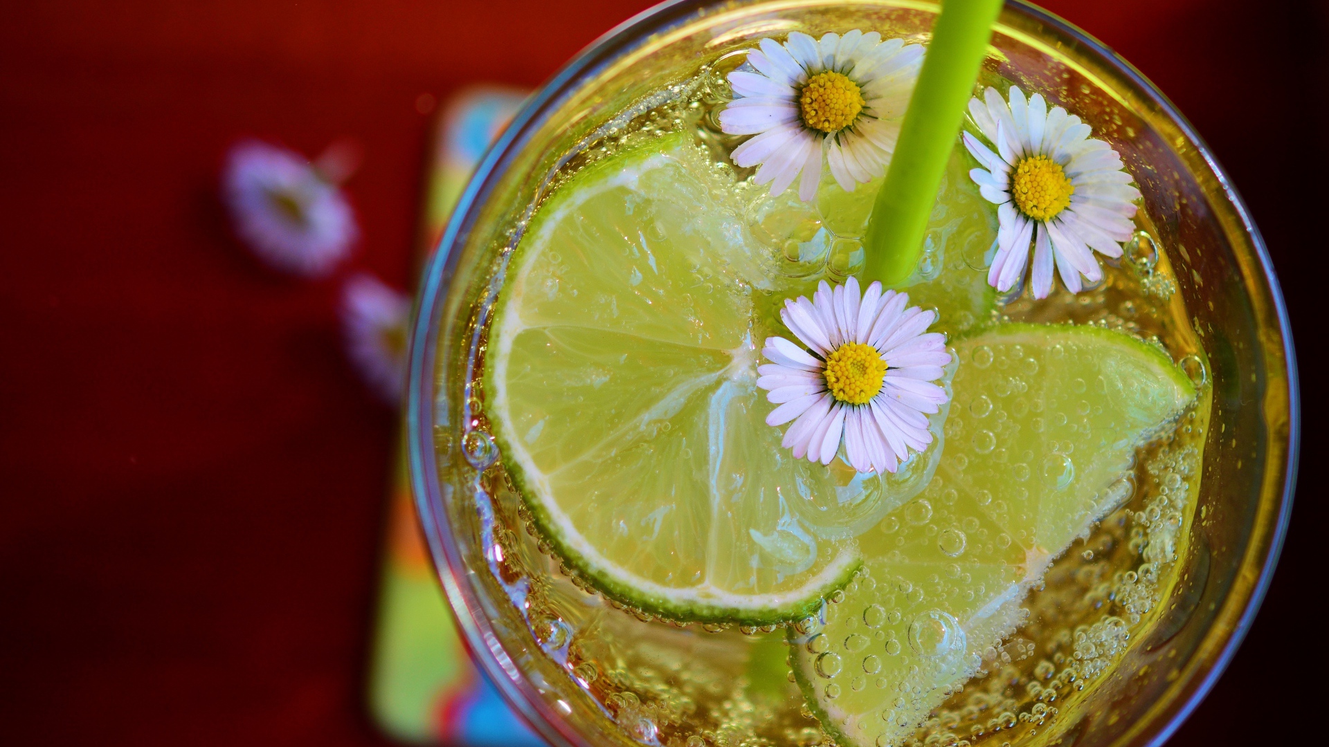 Газированный напиток с кусочками лайма и ромашками в стакане 