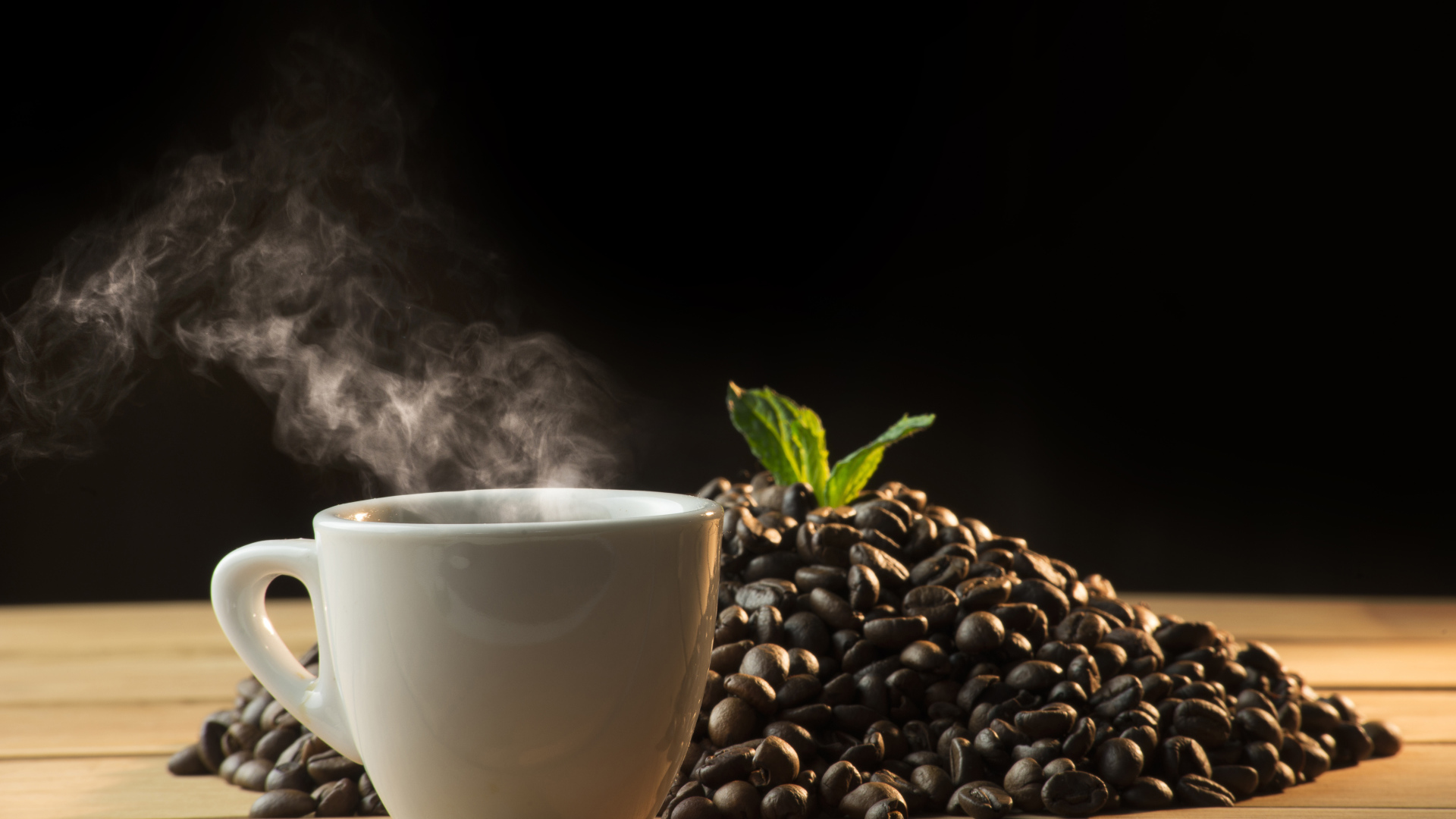 Кофейные зерна на столе с чашкой горячего кофе 