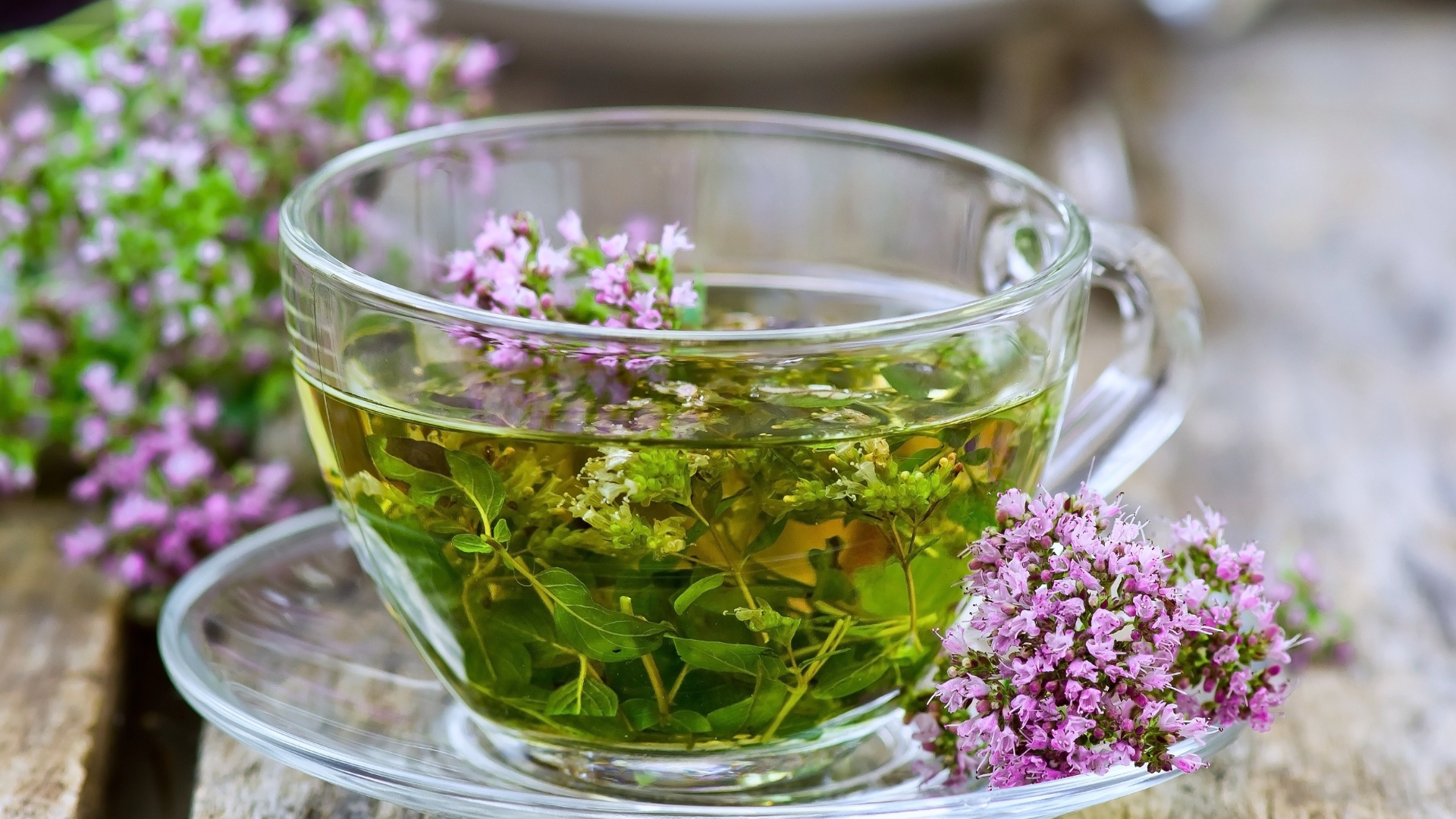 Стеклянная чашка зеленого чая с цветами чабреца