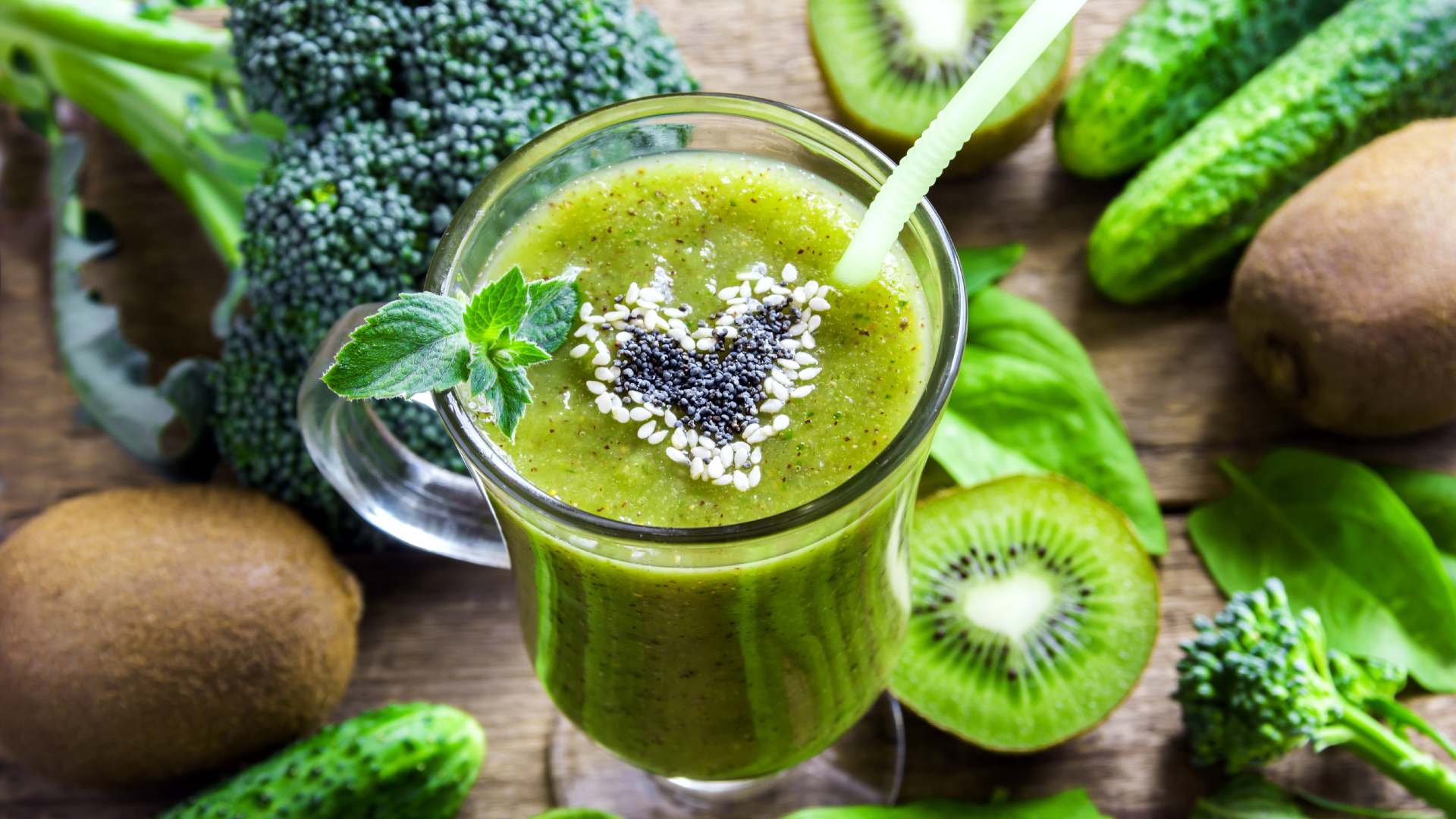 Стакан зеленого смузи на столе с киви, огурцами и брокколи