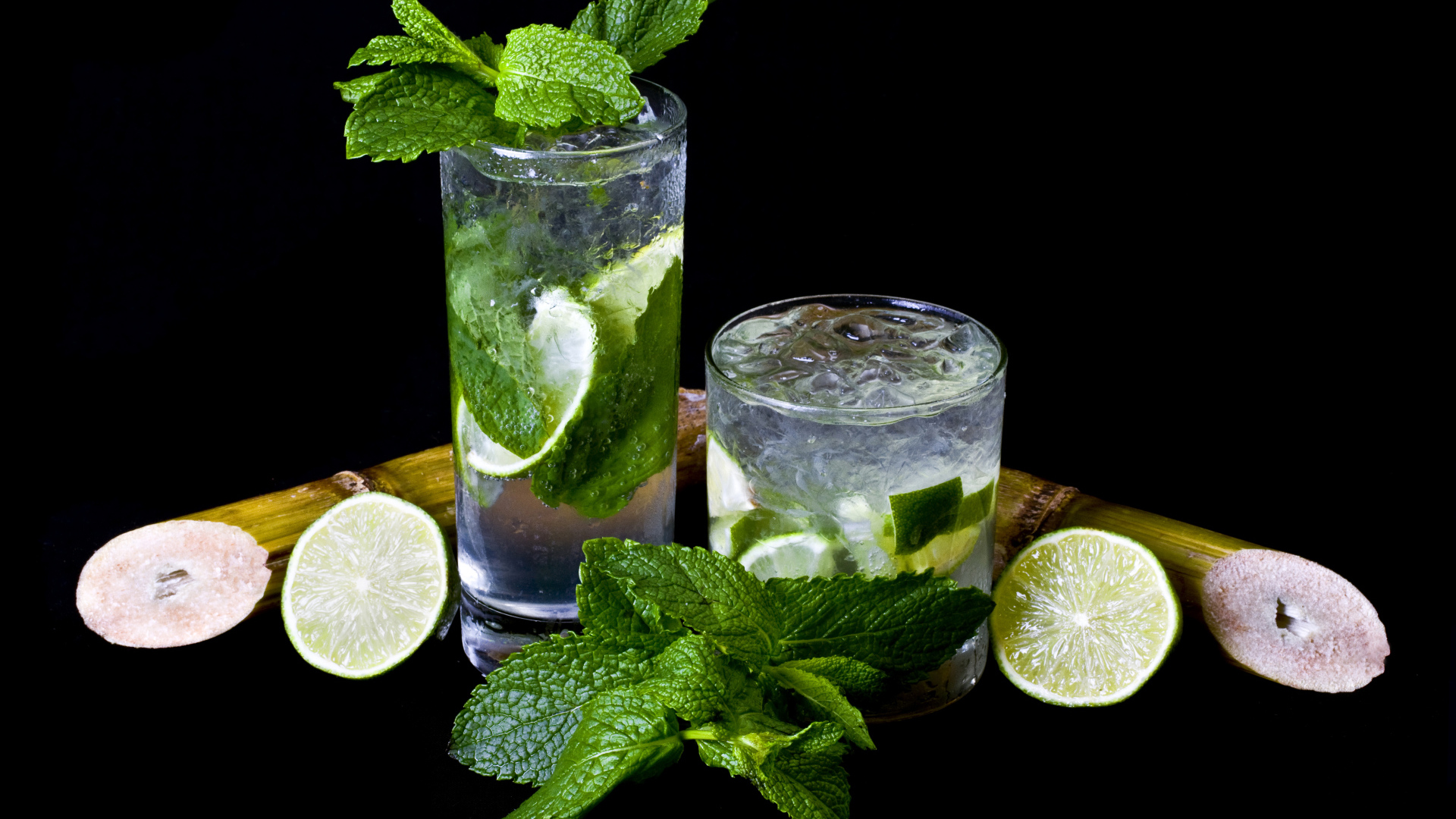 Напиток мохито в стаканах с лаймом и листьями мяты на черном фоне