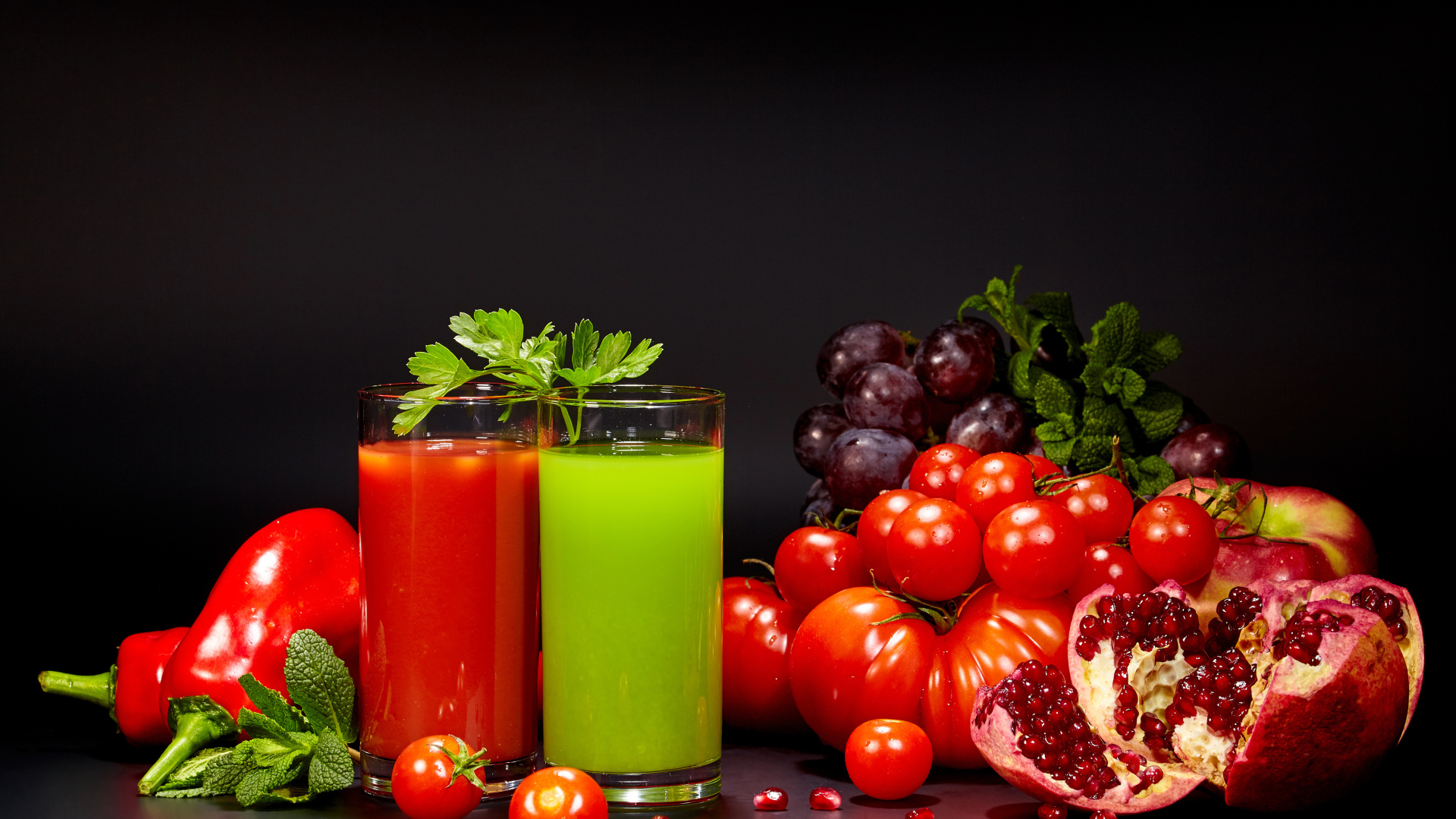 Два стакана сока на столе со свежими помидорами, перцем, гранатом, виноградом и зеленью