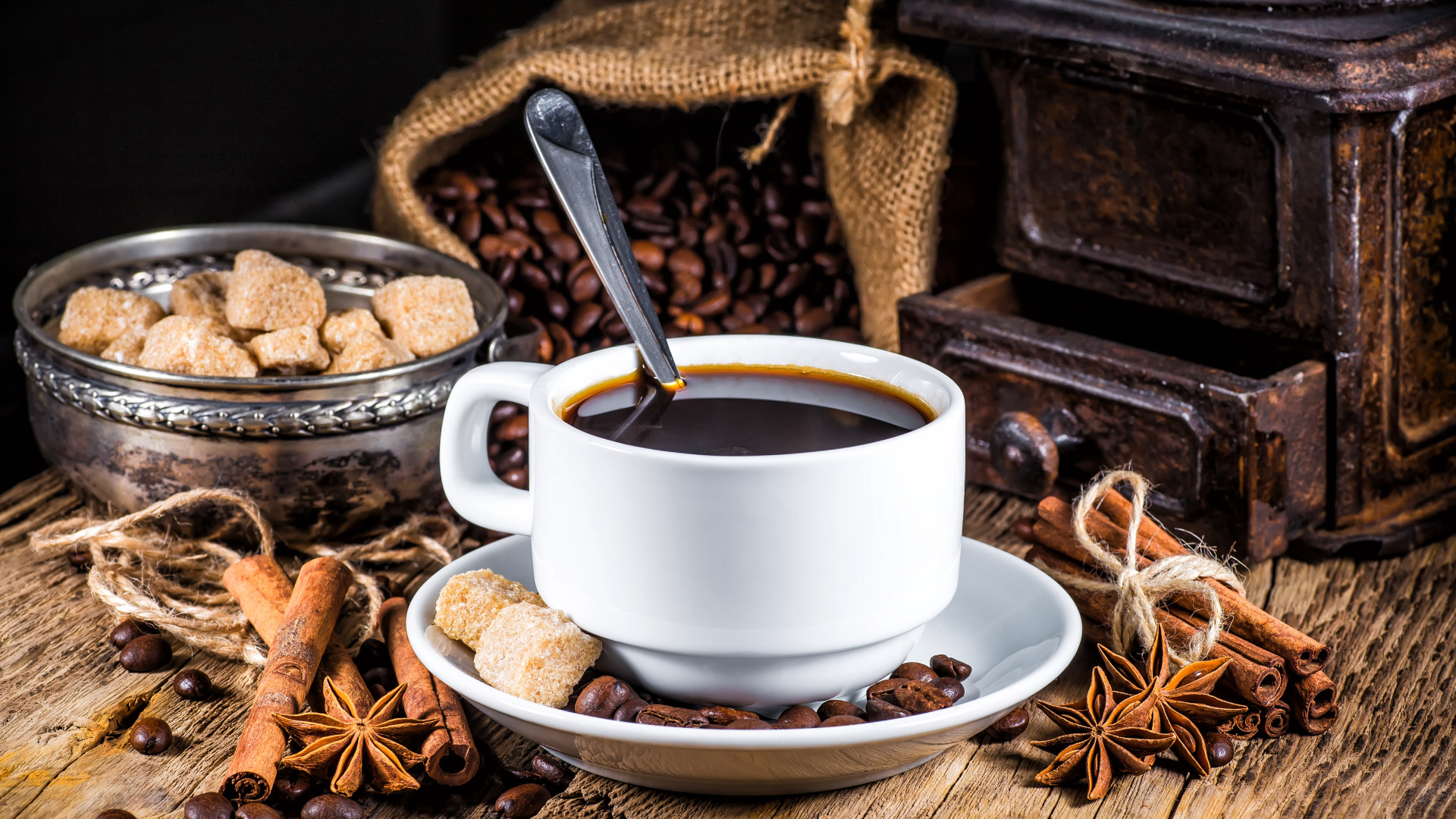 Белая чашка кофе на столе с сахаром, корицей и бадьяном 