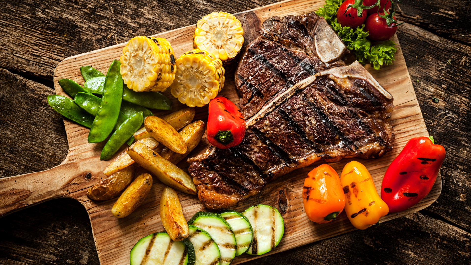 Кусок мяса на разделочной доске с овощами