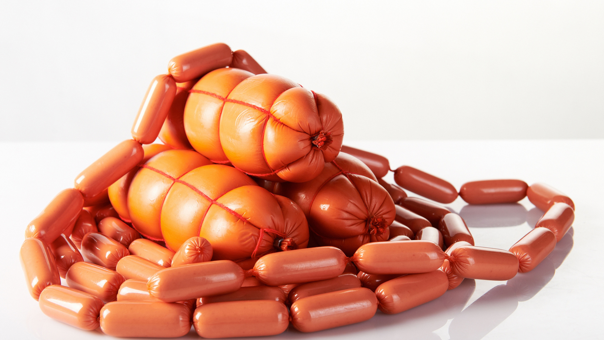 Свежие сосиски и колбаса на белом фоне