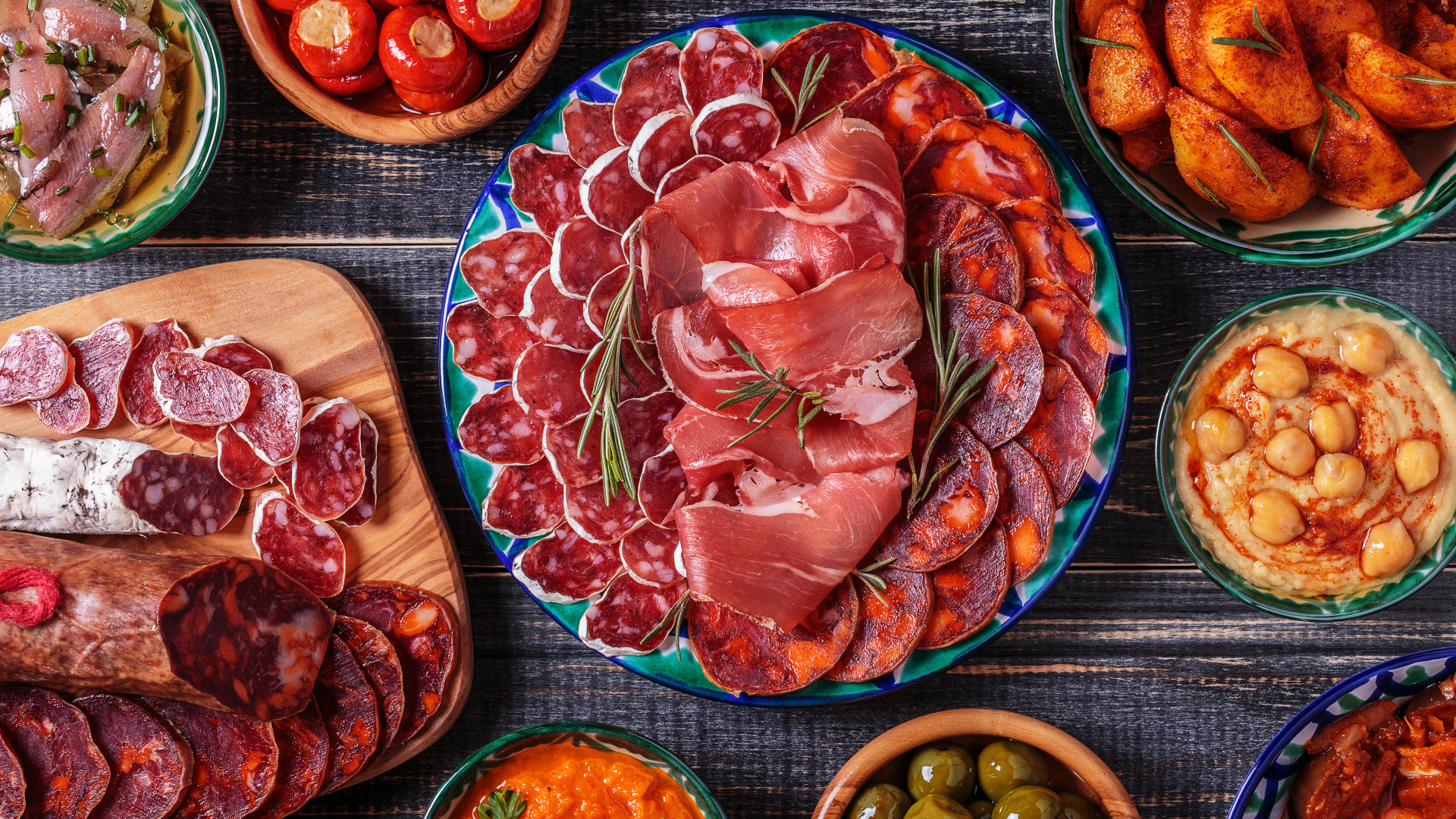 Большая тарелка с мясной нарезкой в центре праздничного стола