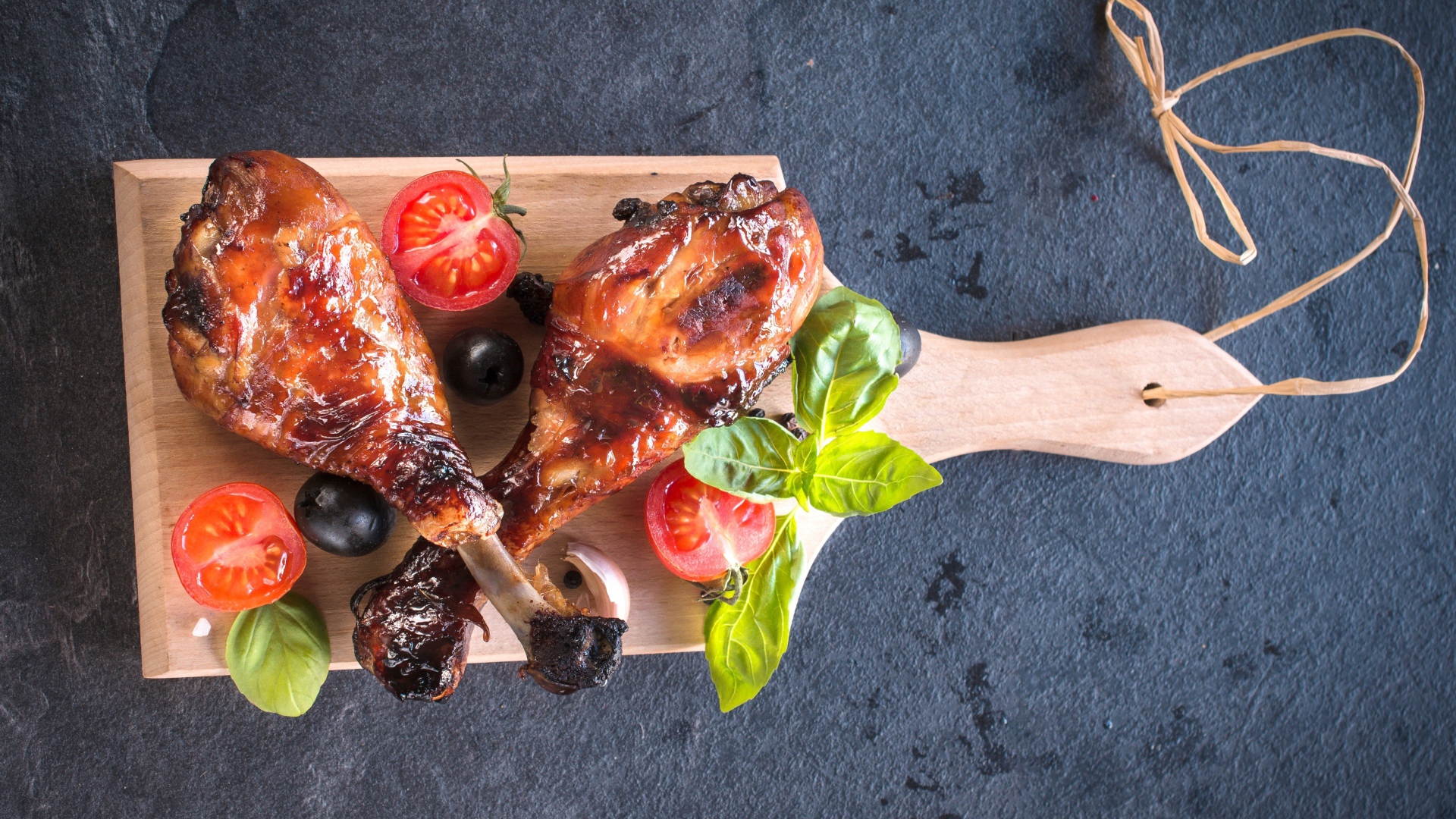 Две зажаренных куриных ножки с овощами на разделочной доске