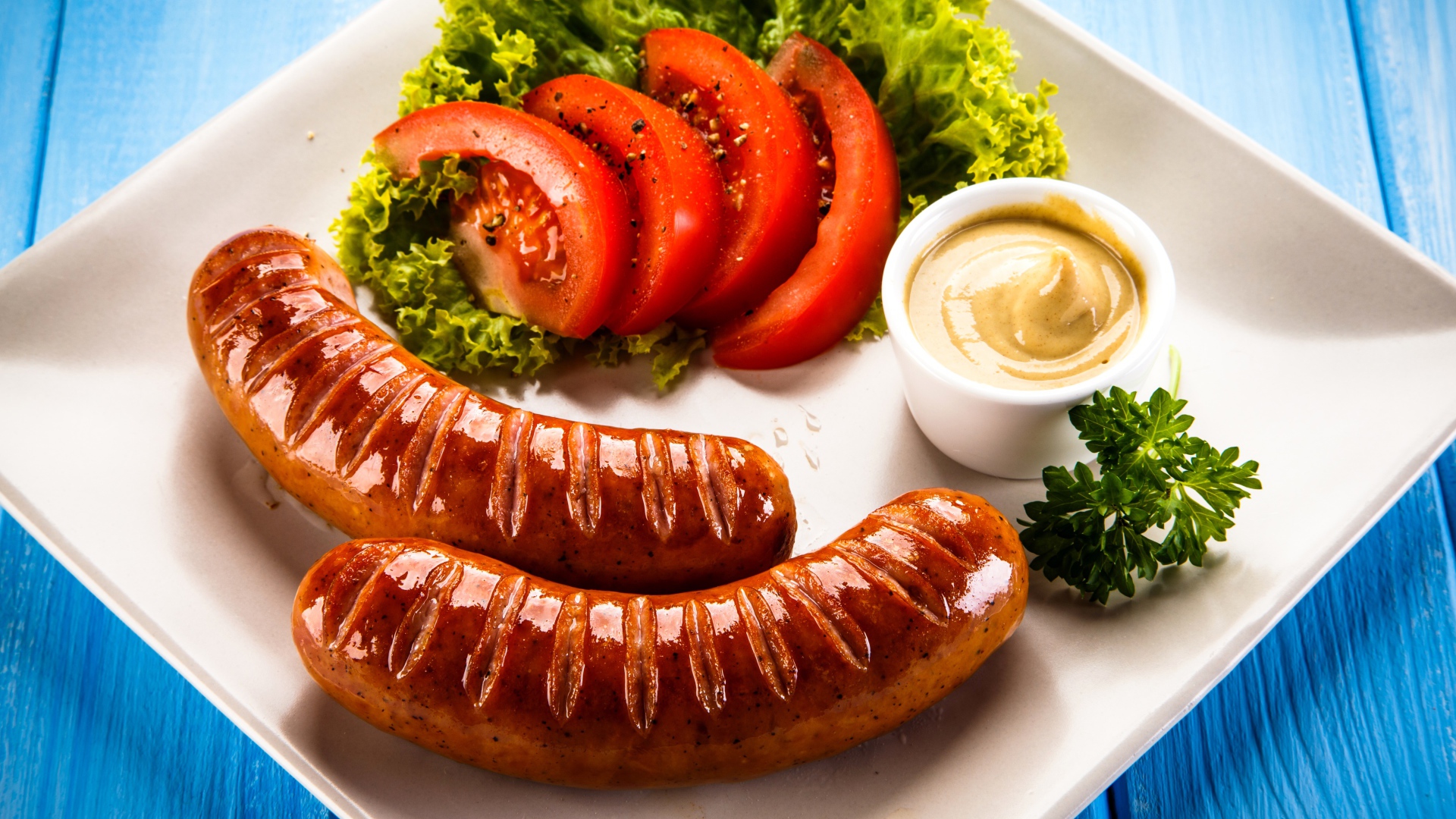 Две сосиски гриль на тарелке с овощами и горчицей