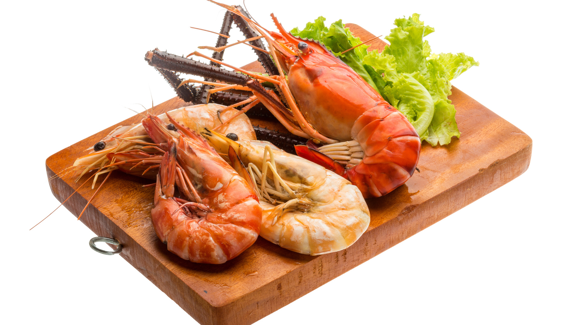 Вареные креветки с листьями салата на разделочной доске