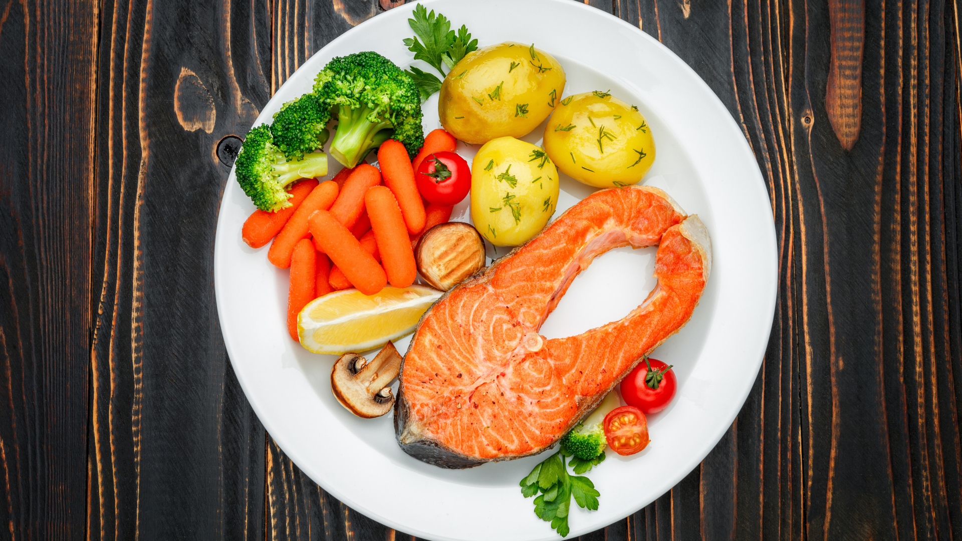 Красная рыба с овощами на белой тарелке на столе