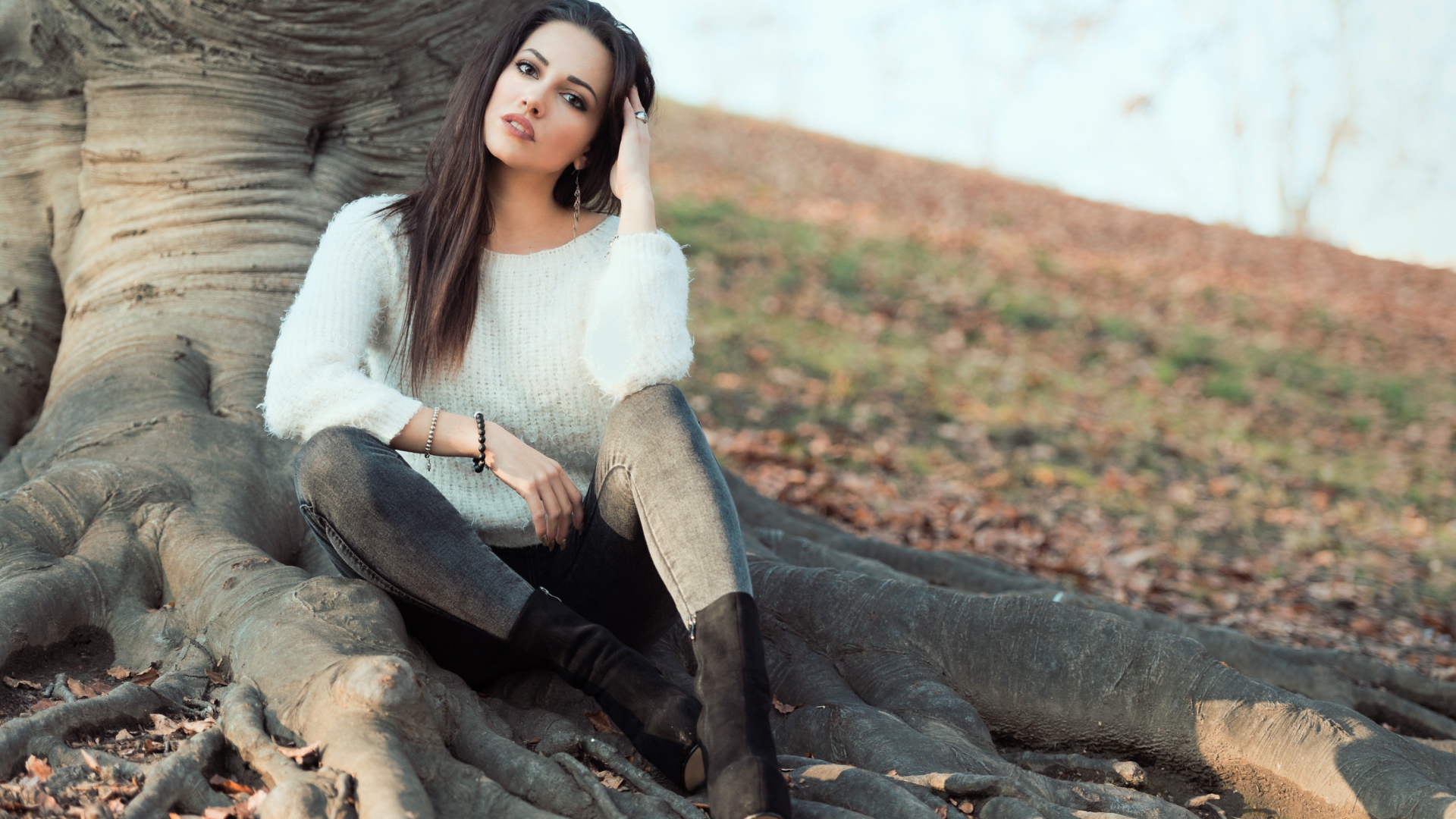 Красивая девушка сидит у дерева