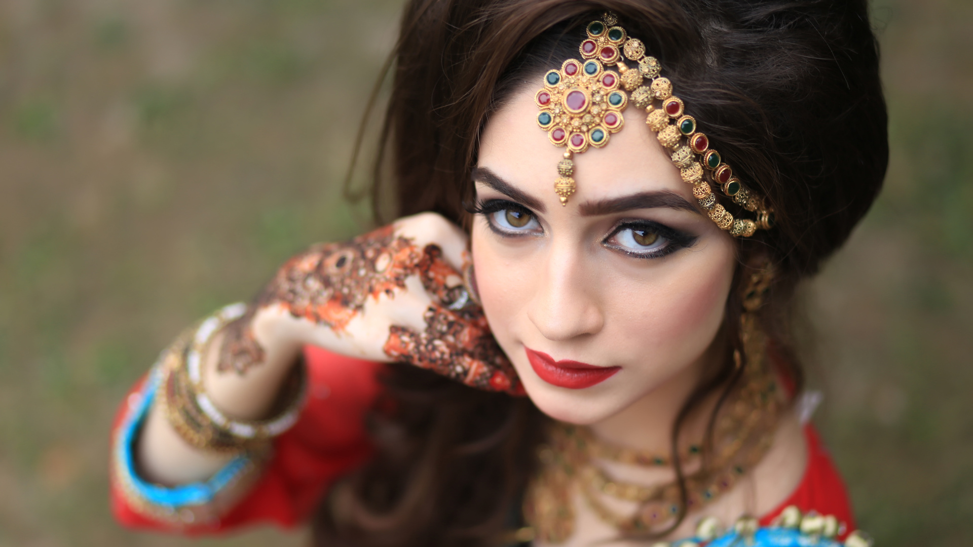 Красивая кареглазая девушка в индийском костюме с рисунками на руках 