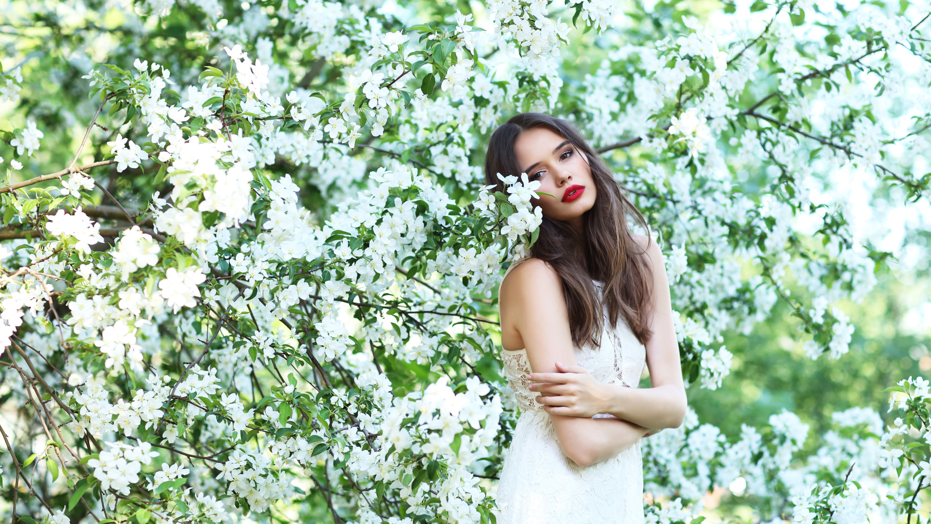 Красивая шатенка в цветущих ветках яблони