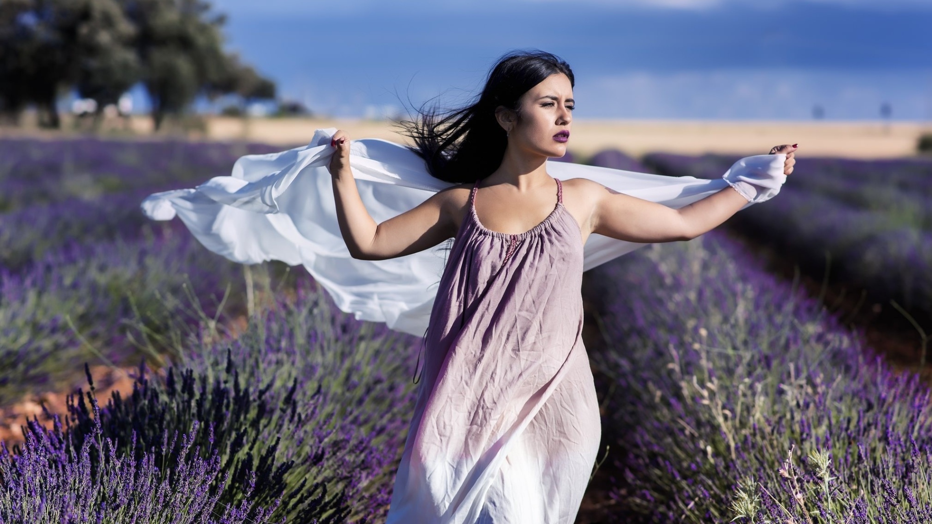 Красивая брюнетка в сарафане гуляет по лавандовому полю