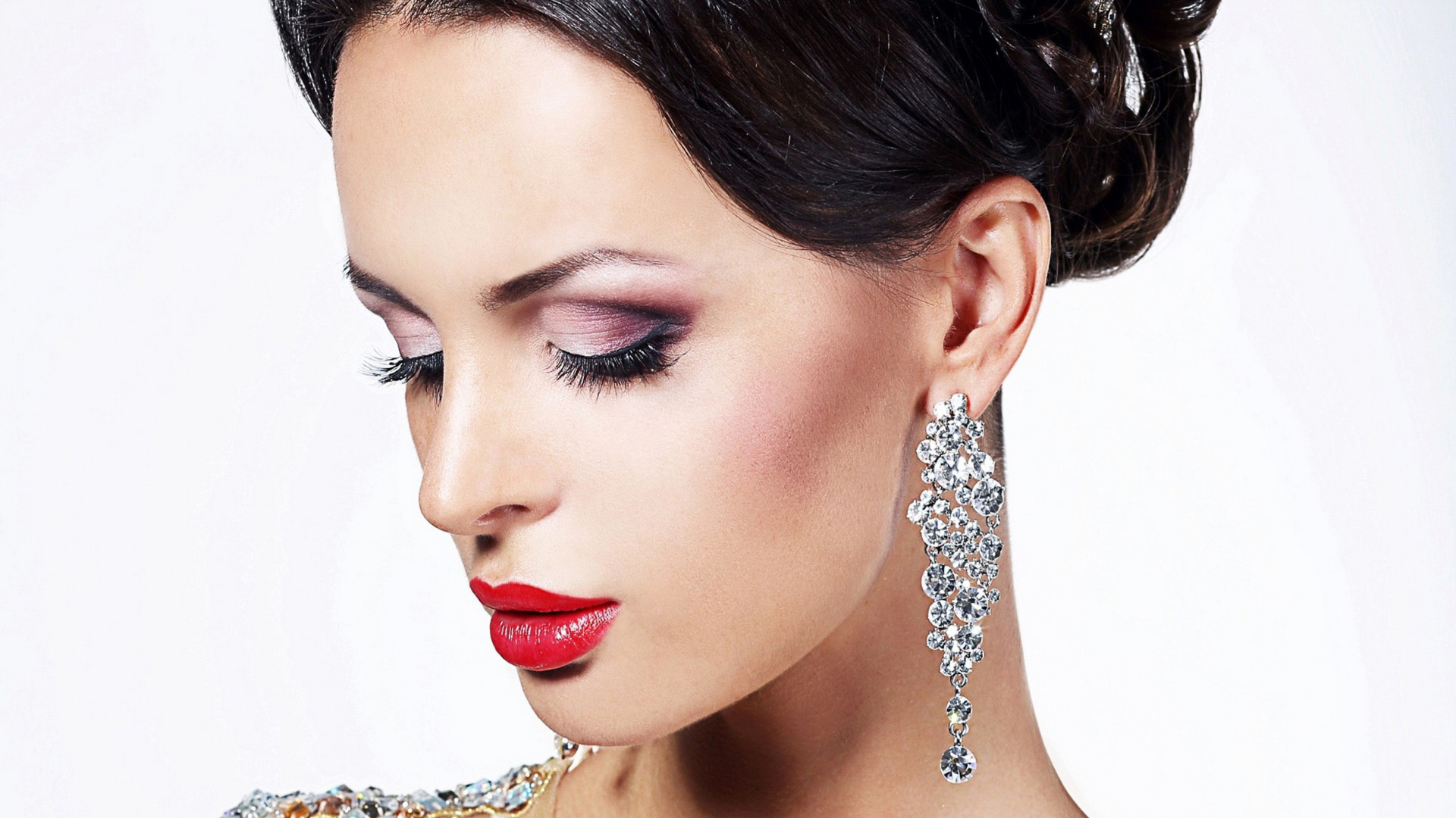 Красивая брюнетка в дорогих украшениях на белом фоне