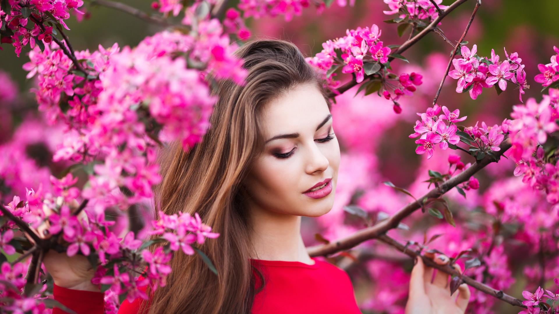 Красивая нежная шатенка у цветущей розовыми цветами ветки
