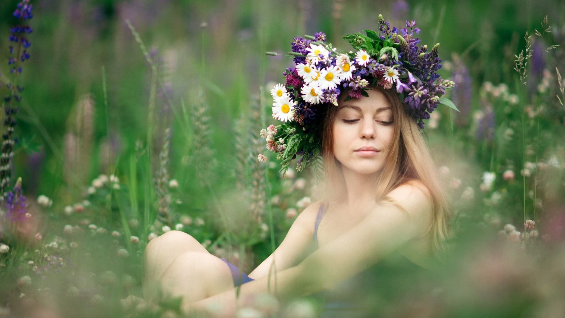 Красивая девушка с венком из полевых цветов на голове летом 