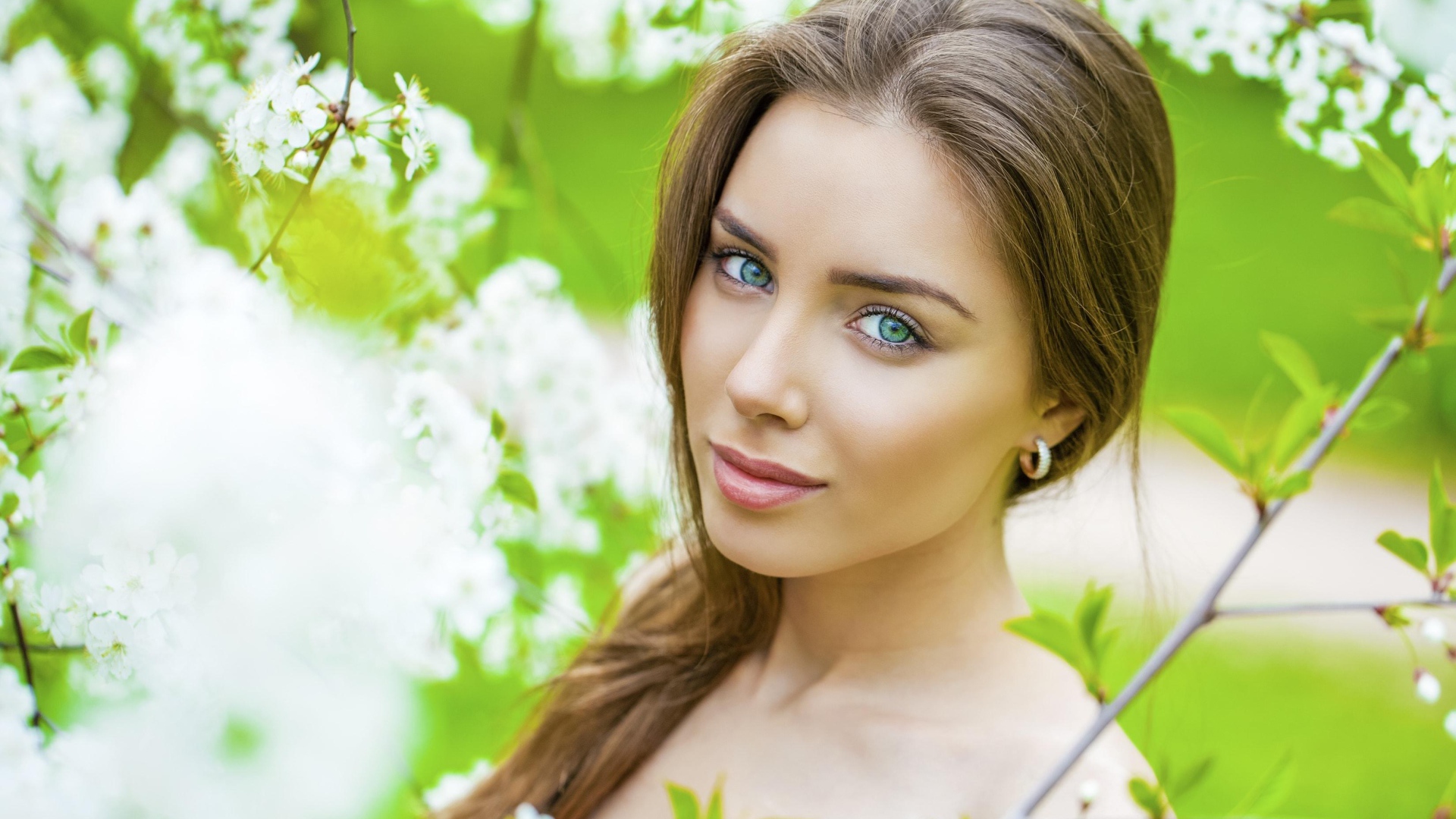 Красивая зеленоглазая девушка у цветущей вишни 
