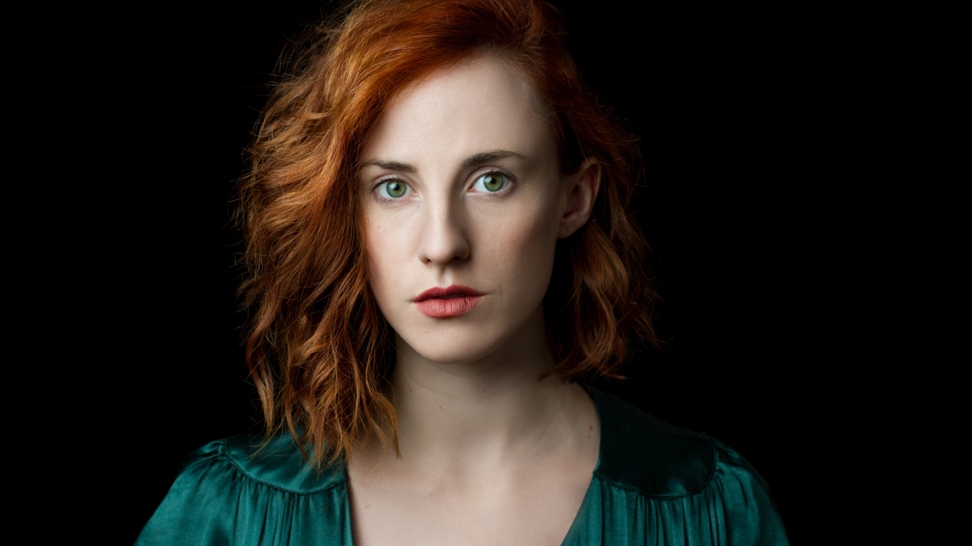 Красивая зеленоглазая рыжеволосая девушка на черном фоне 
