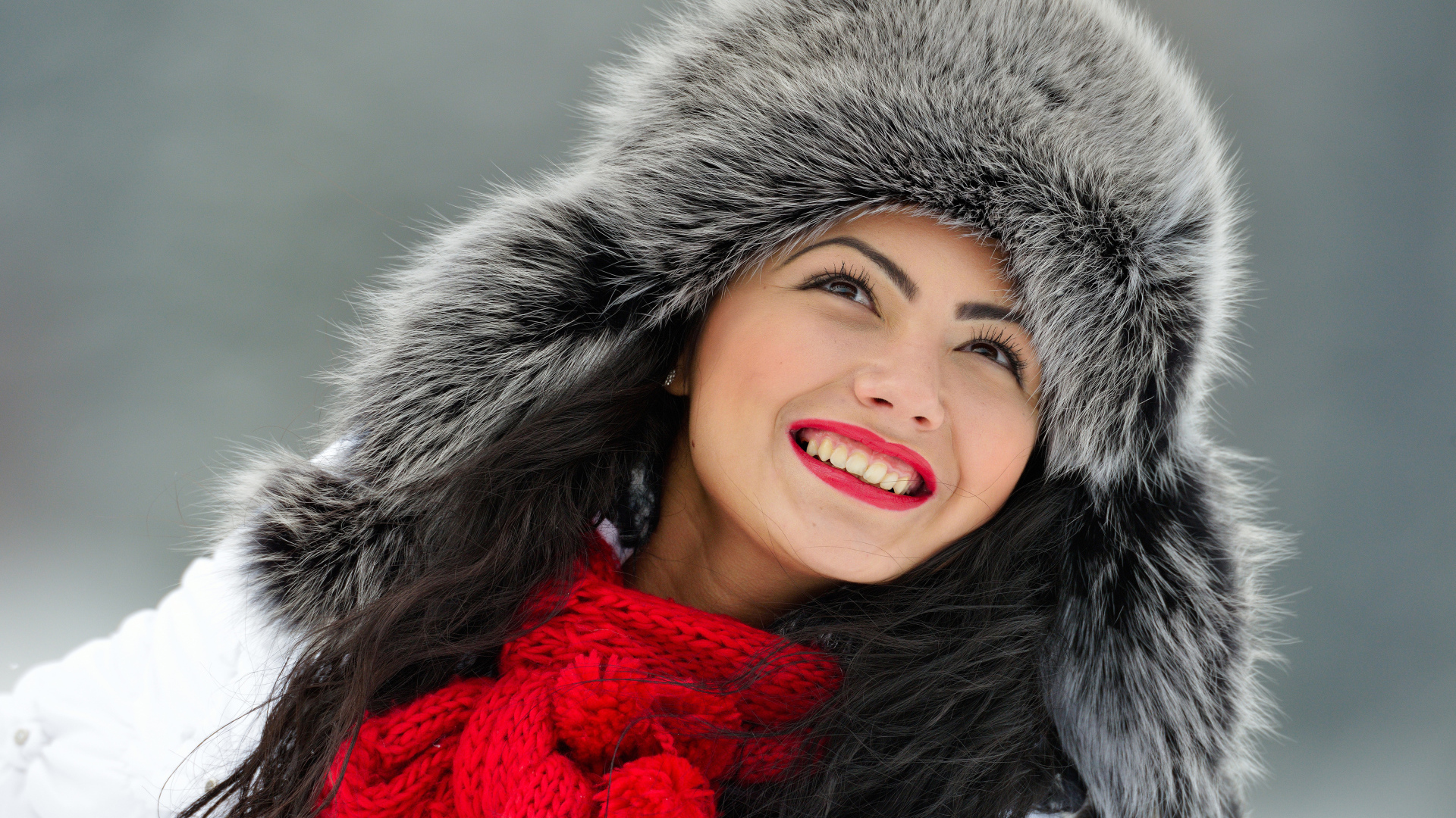 Красивая улыбающаяся брюнетка в теплой зимней шапке