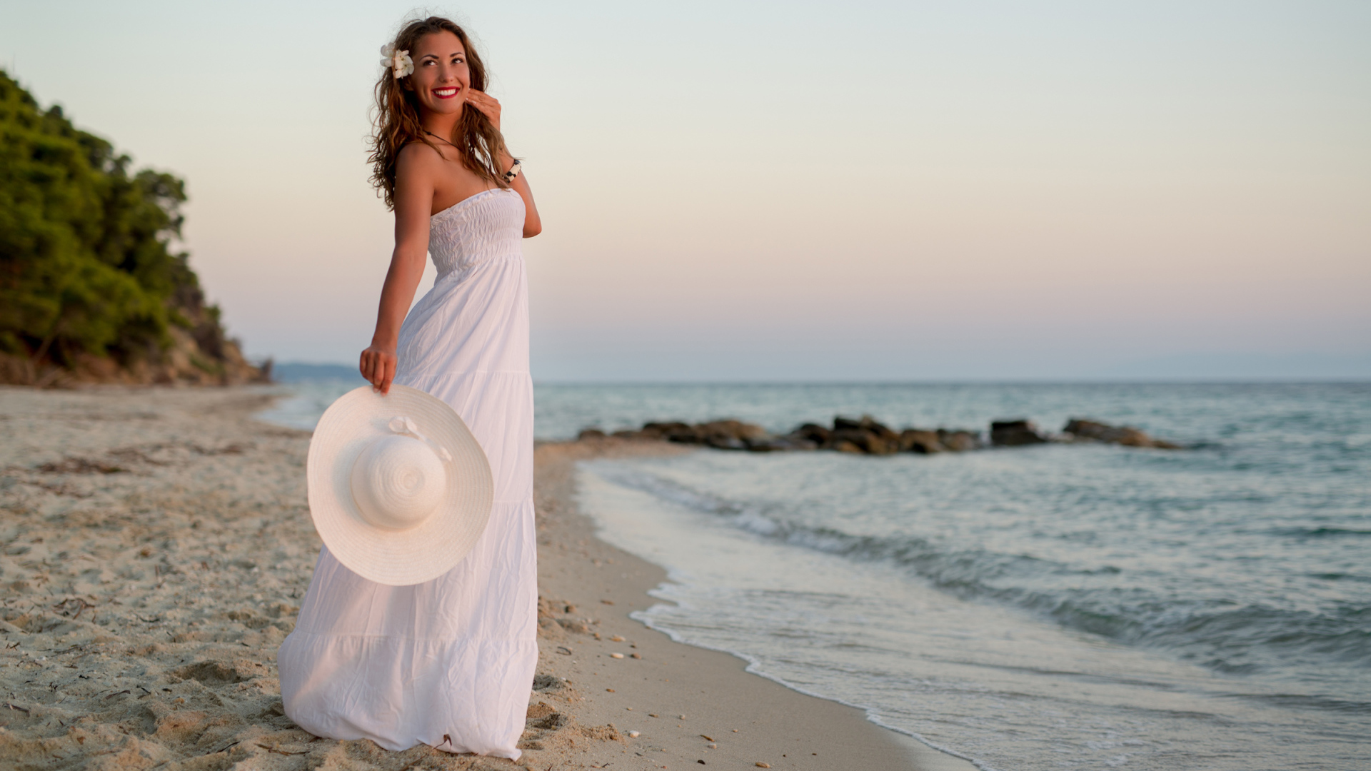 Красивая улыбающаяся девушка в белом платье на побережье