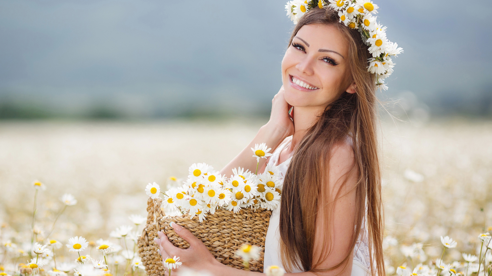 Красивая улыбающаяся девушка на поле с корзиной ромашек