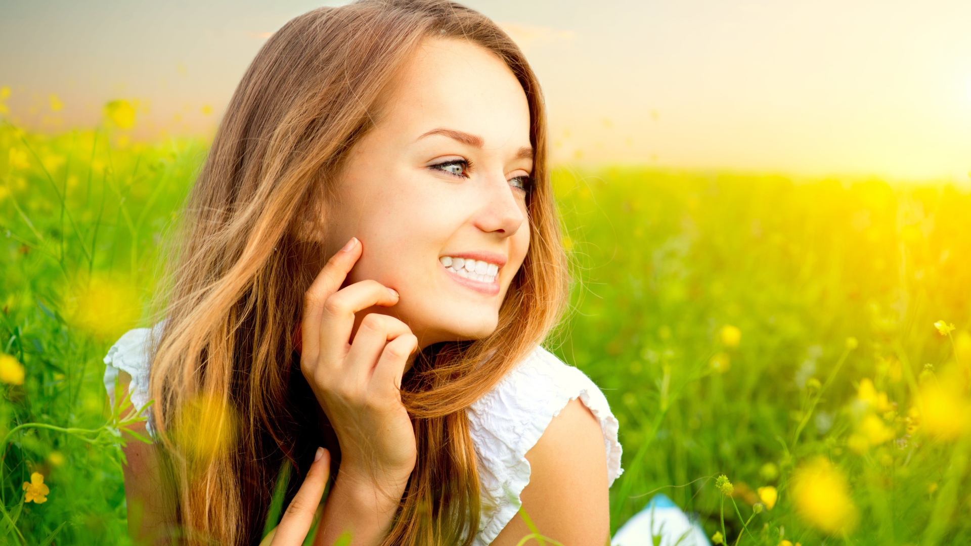 Красивая улыбающаяся молодая девушка лежит в зеленой траве