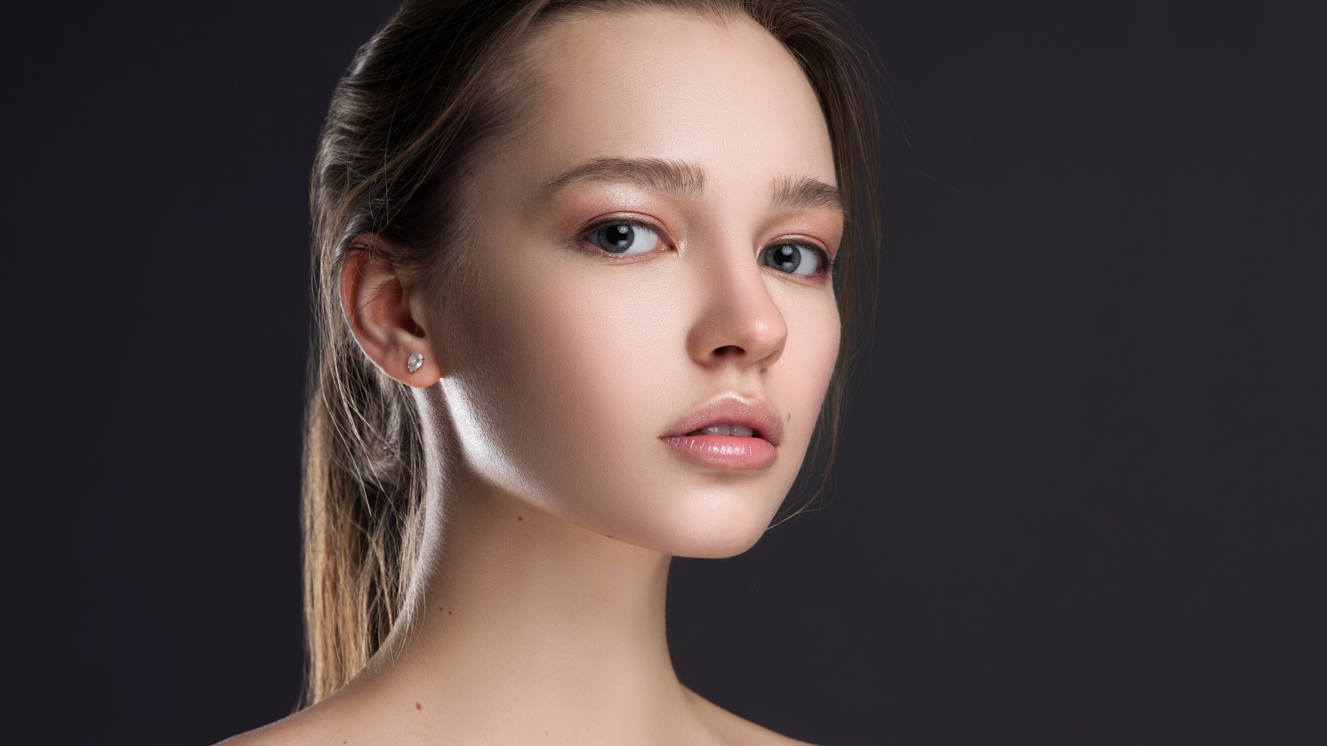 Нежная настоящая девушка шатенка на сером фоне