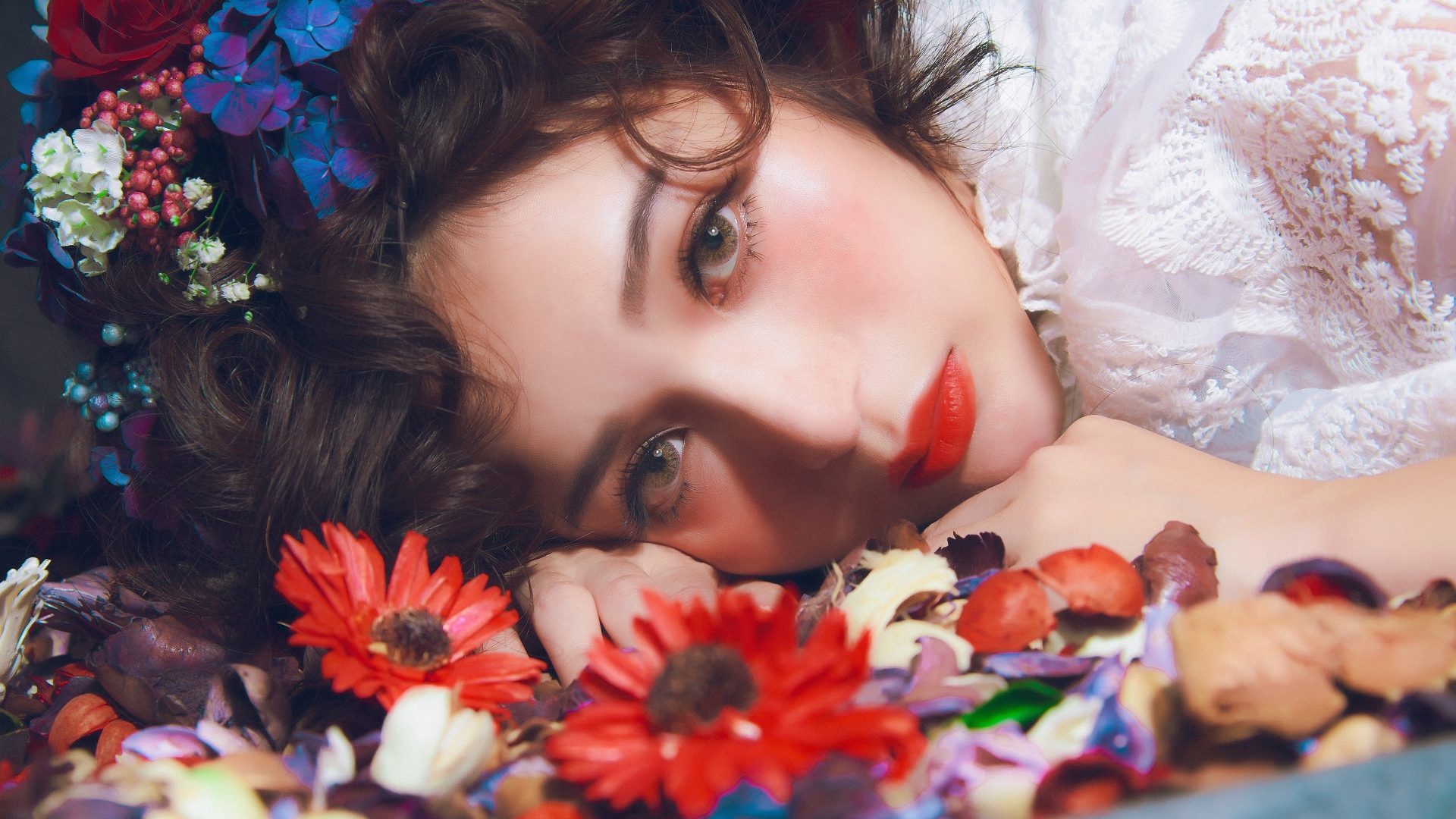 Молодая красивая девушка лежит цветами в волосах