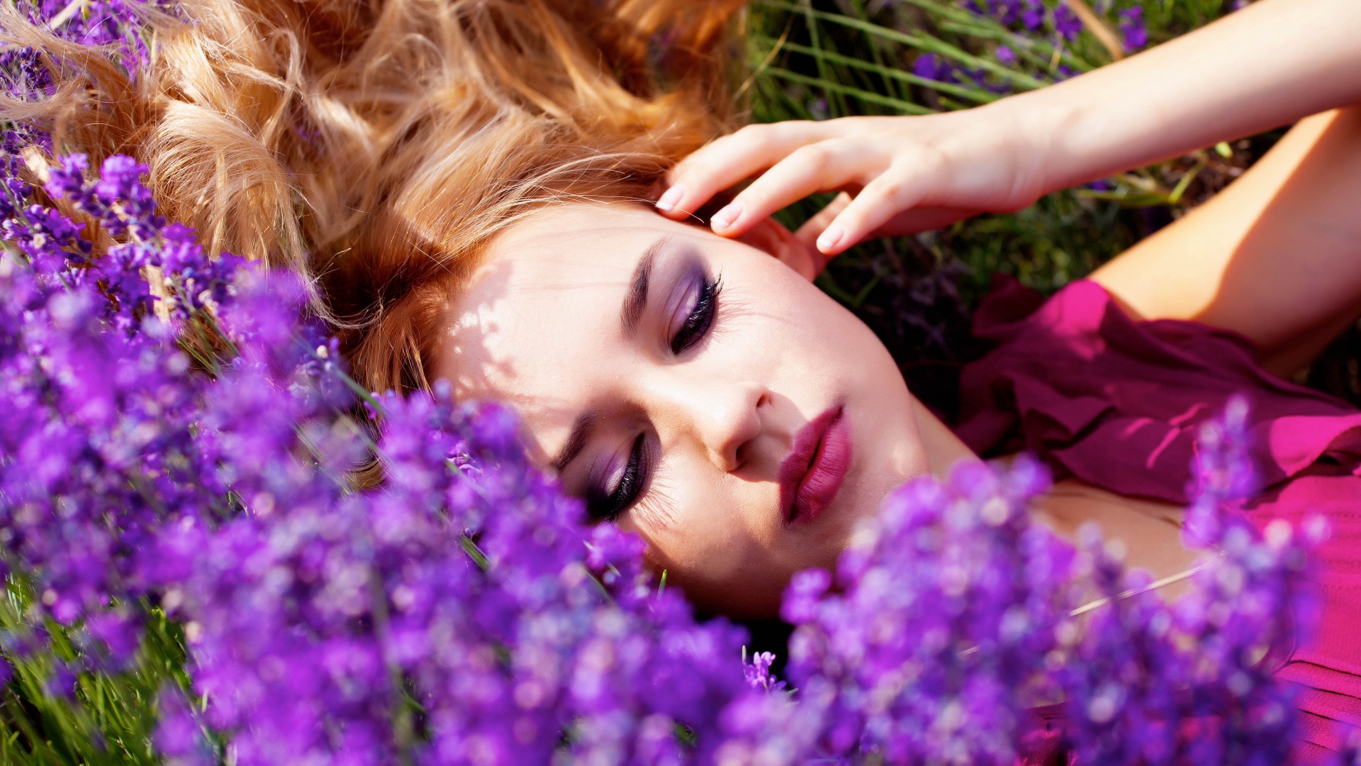 Молодая красивая девушка лежит на траве с сиреневыми цветами