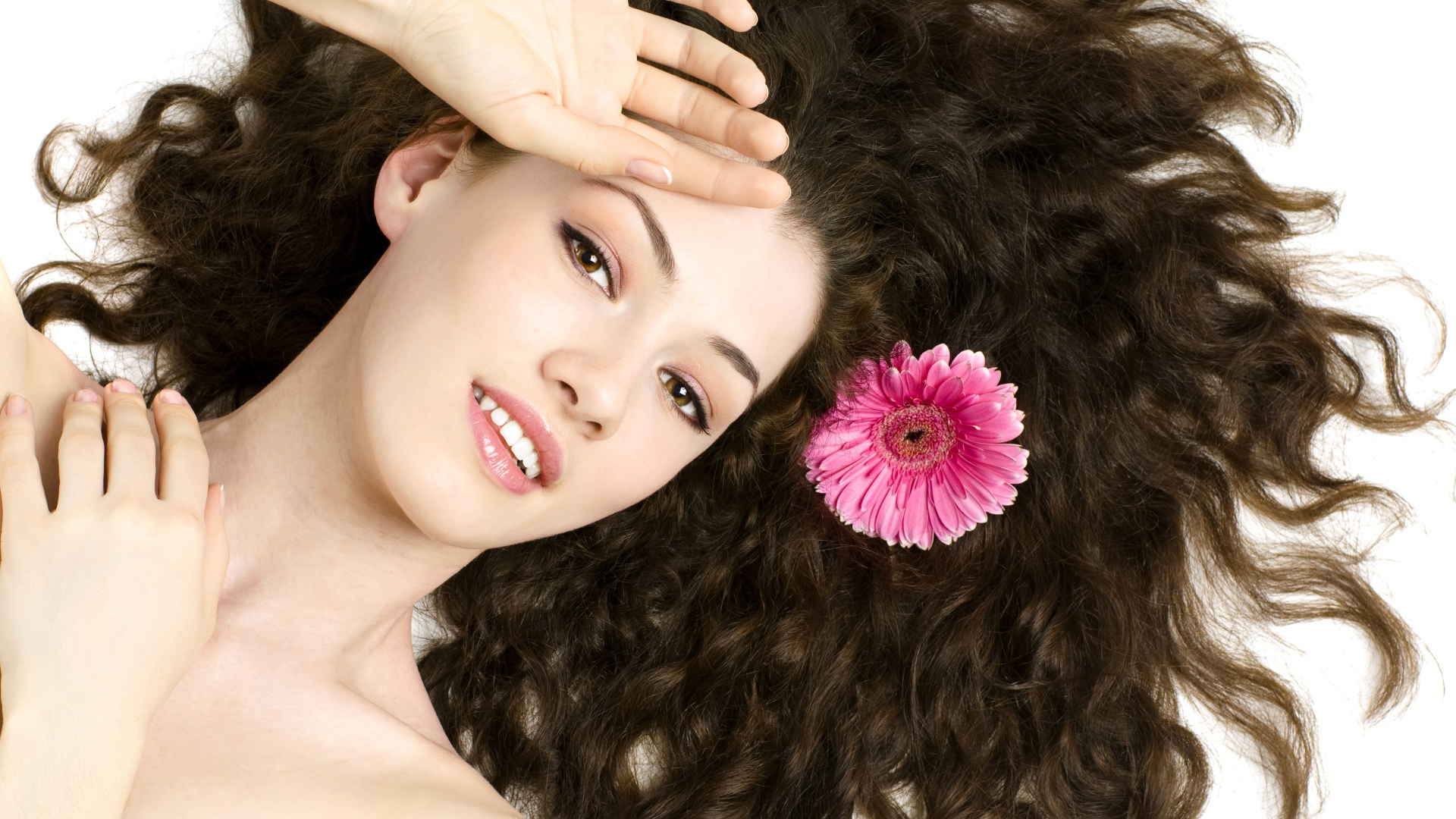 Молодая шатенка с розовым цветком герберы в волосах