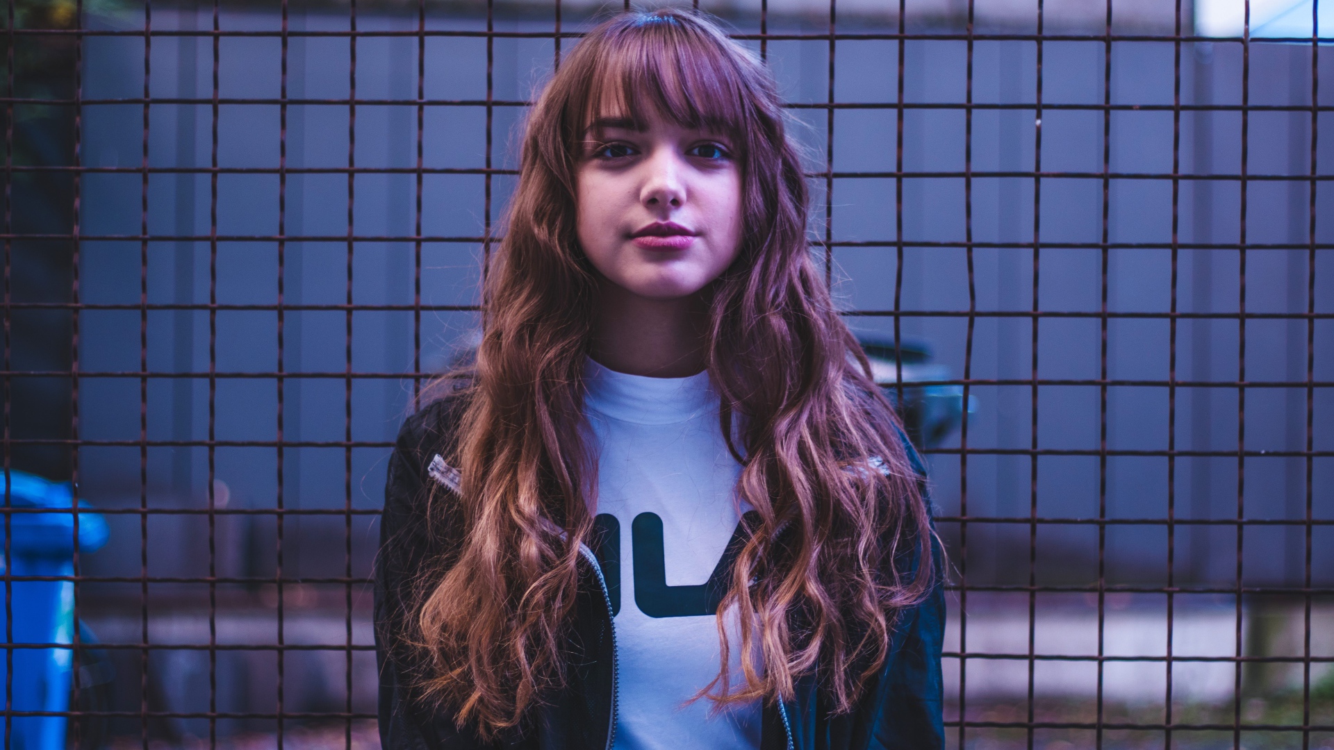 Молодая девушка на фоне железной сетки