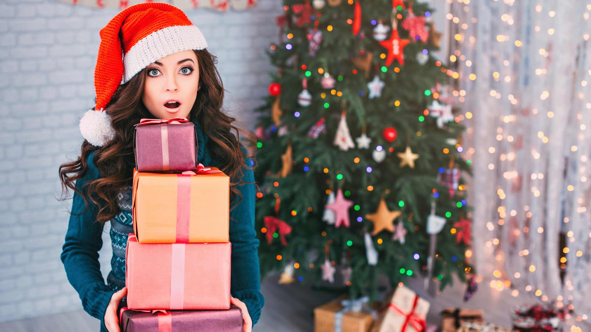 Удивленная девушка с подарками у новогодней елки 