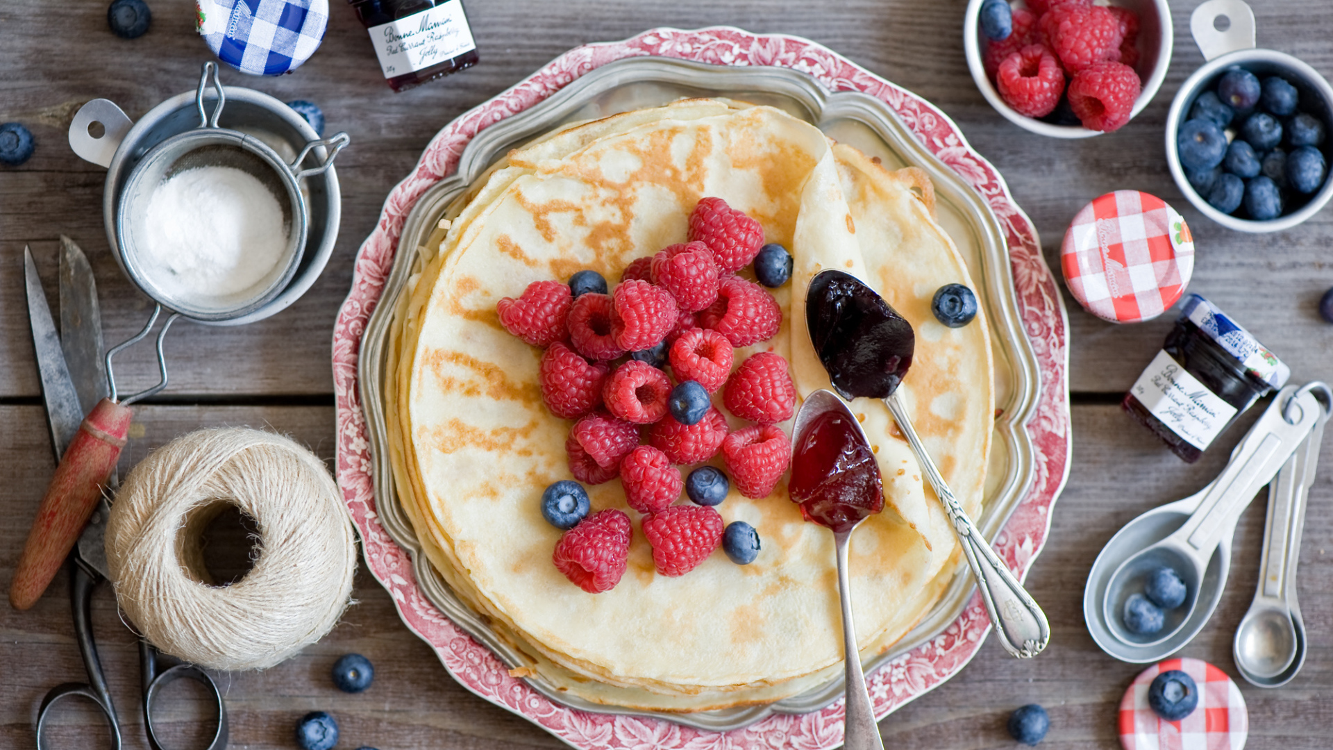 Тонкие блины с малиной и черникой на столе вид сверху