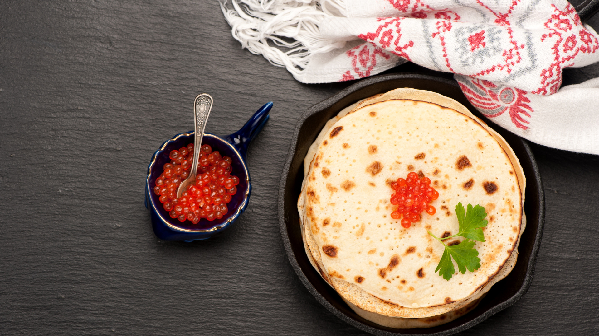 Тонкие блины с красной икрой на столе вид сверху