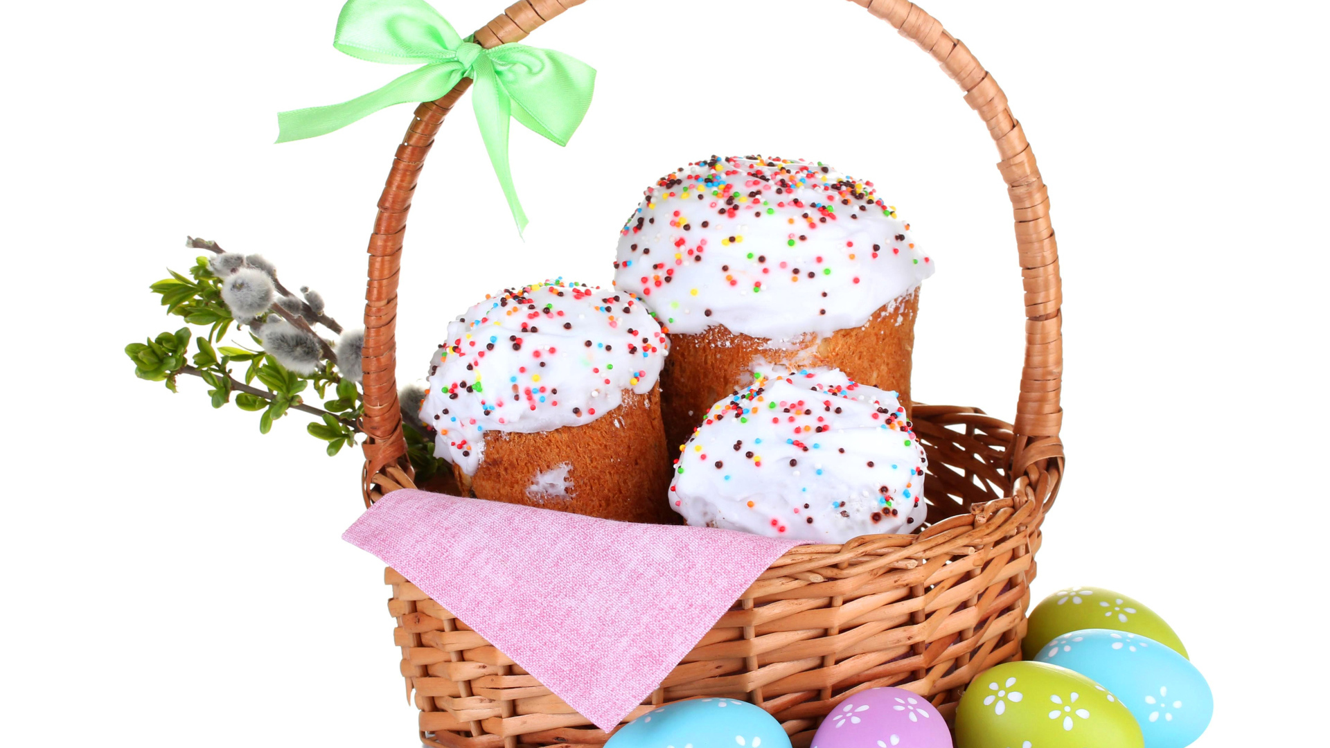 Пасхальные куличи в корзине с крашеными яйцами на белом фоне