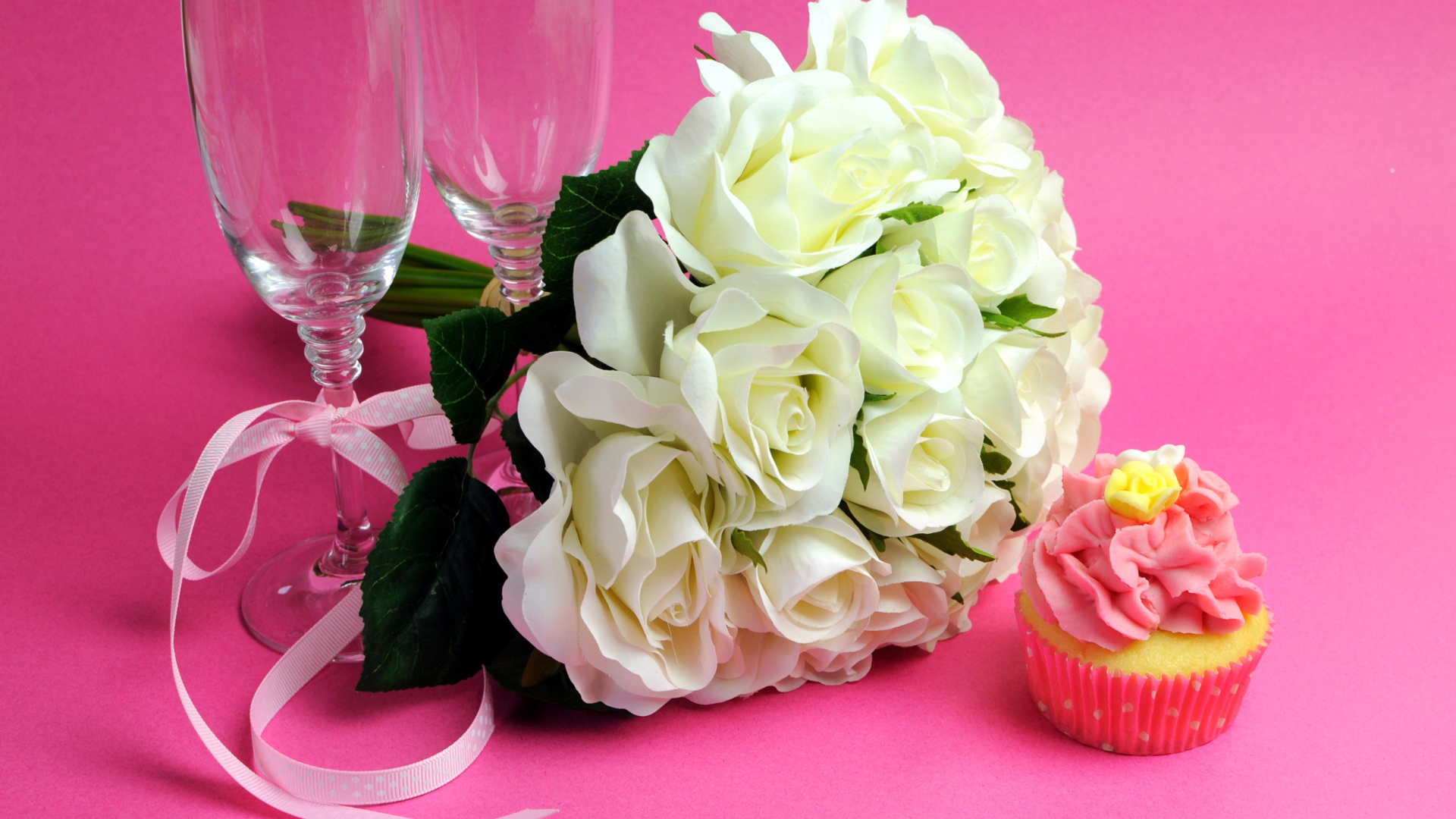 Букет белых роз, пирожное и два бокала на розовом фоне на 8 марта