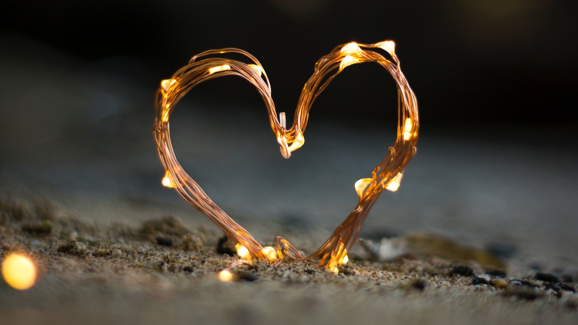 Сердце из гирлянды на песке