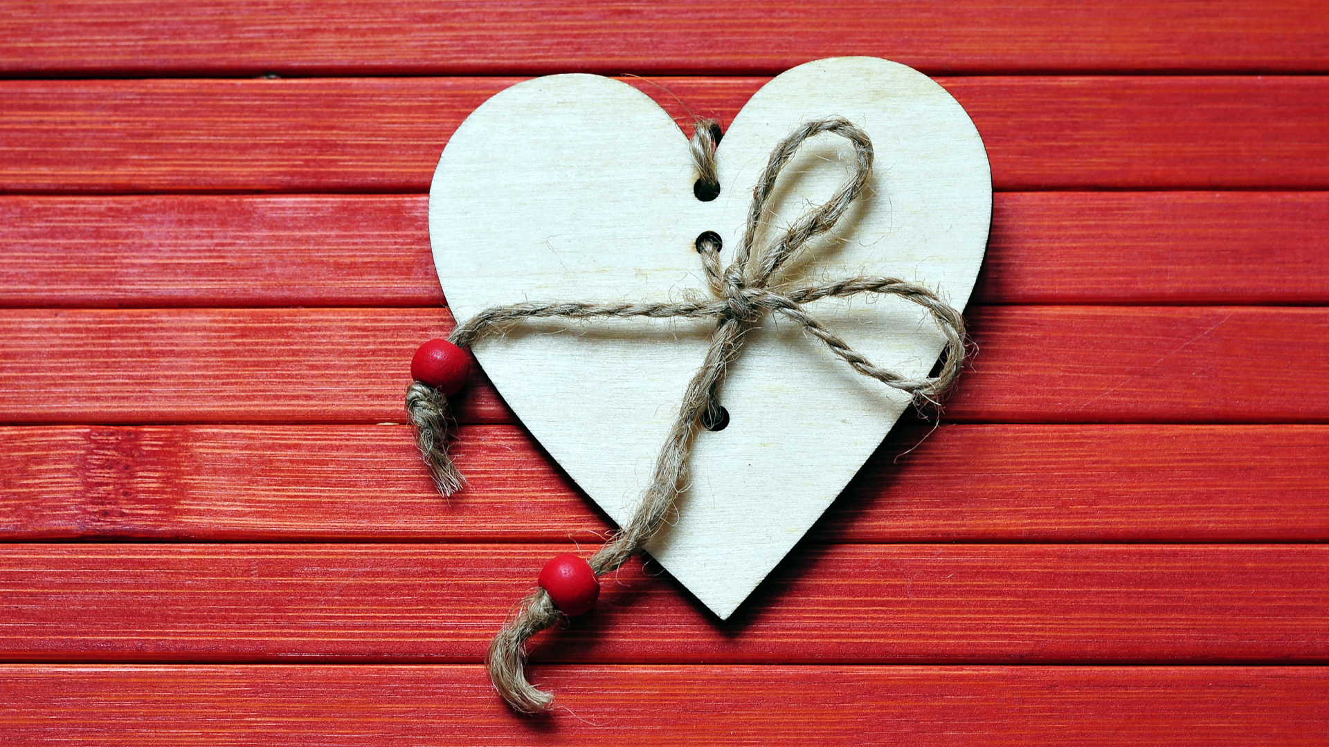 Сердце с веревкой на красном деревянном фоне