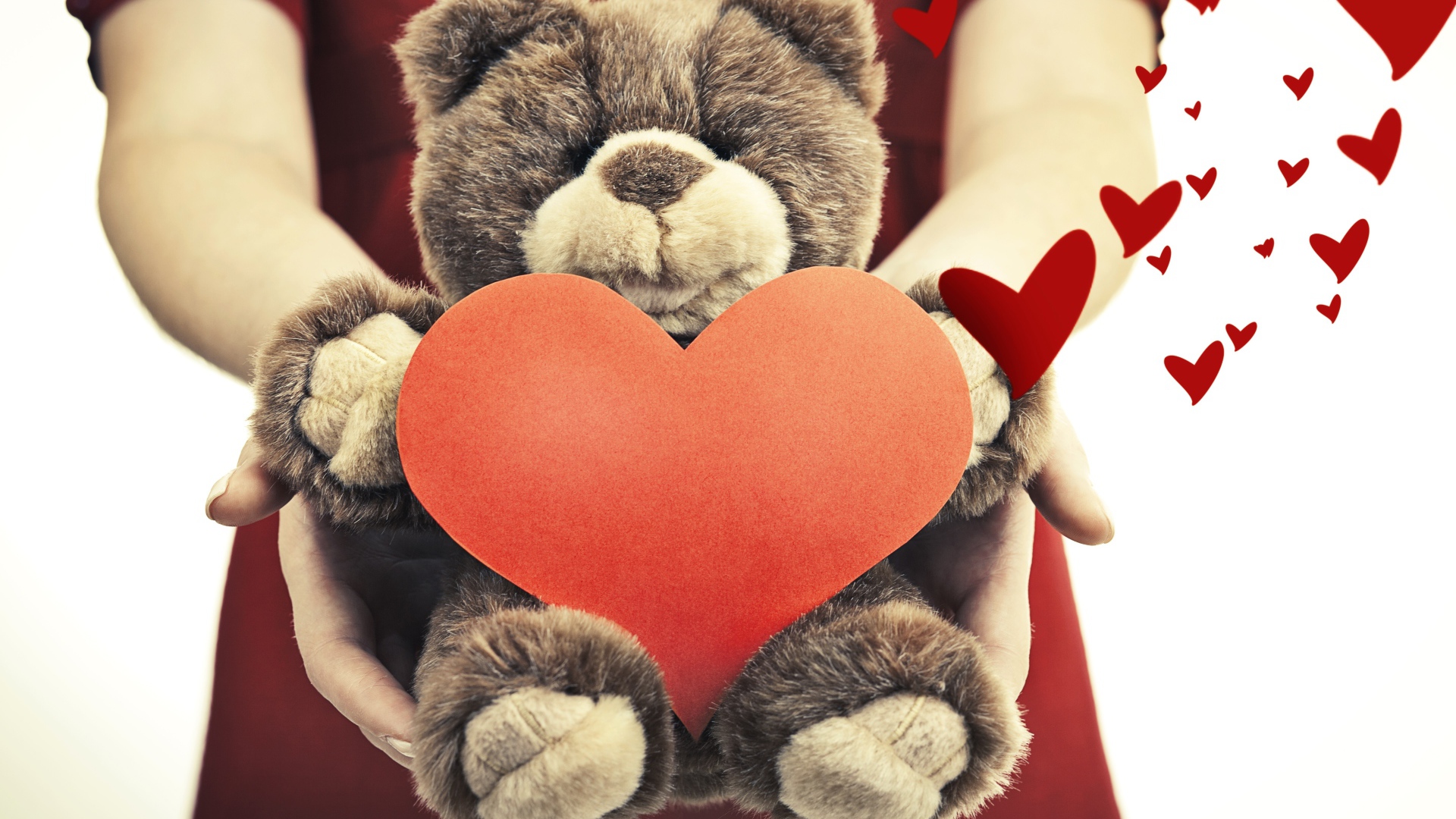 Плюшевый медведь с большим красным сердцем в руках