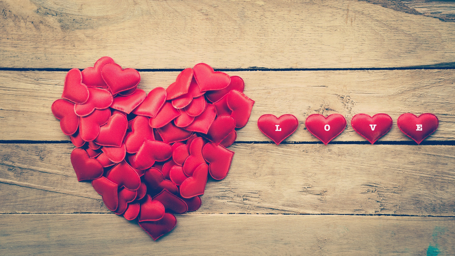 Маленькие красные сердечки на деревянной поверхности 