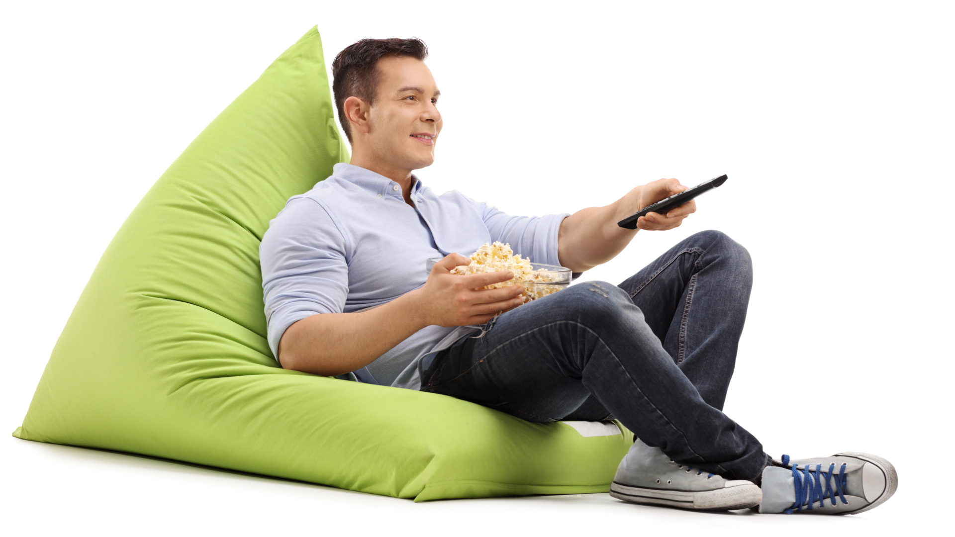 Мужчина с попкорном и пультом от телевизора лежит на зеленой подушке